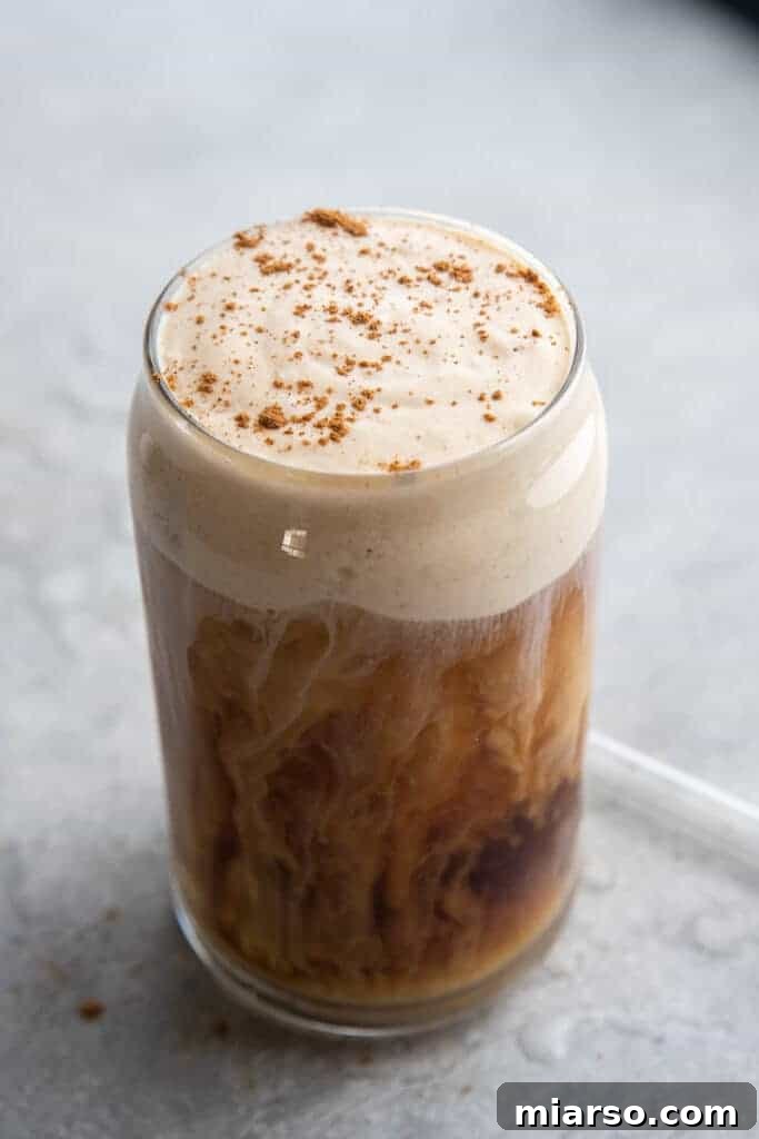 Fall's Ultimate Starbucks Pumpkin Cream Cold Brew 9 Delicious cream swirls mixing into rich cold brew coffee in a clear glass.