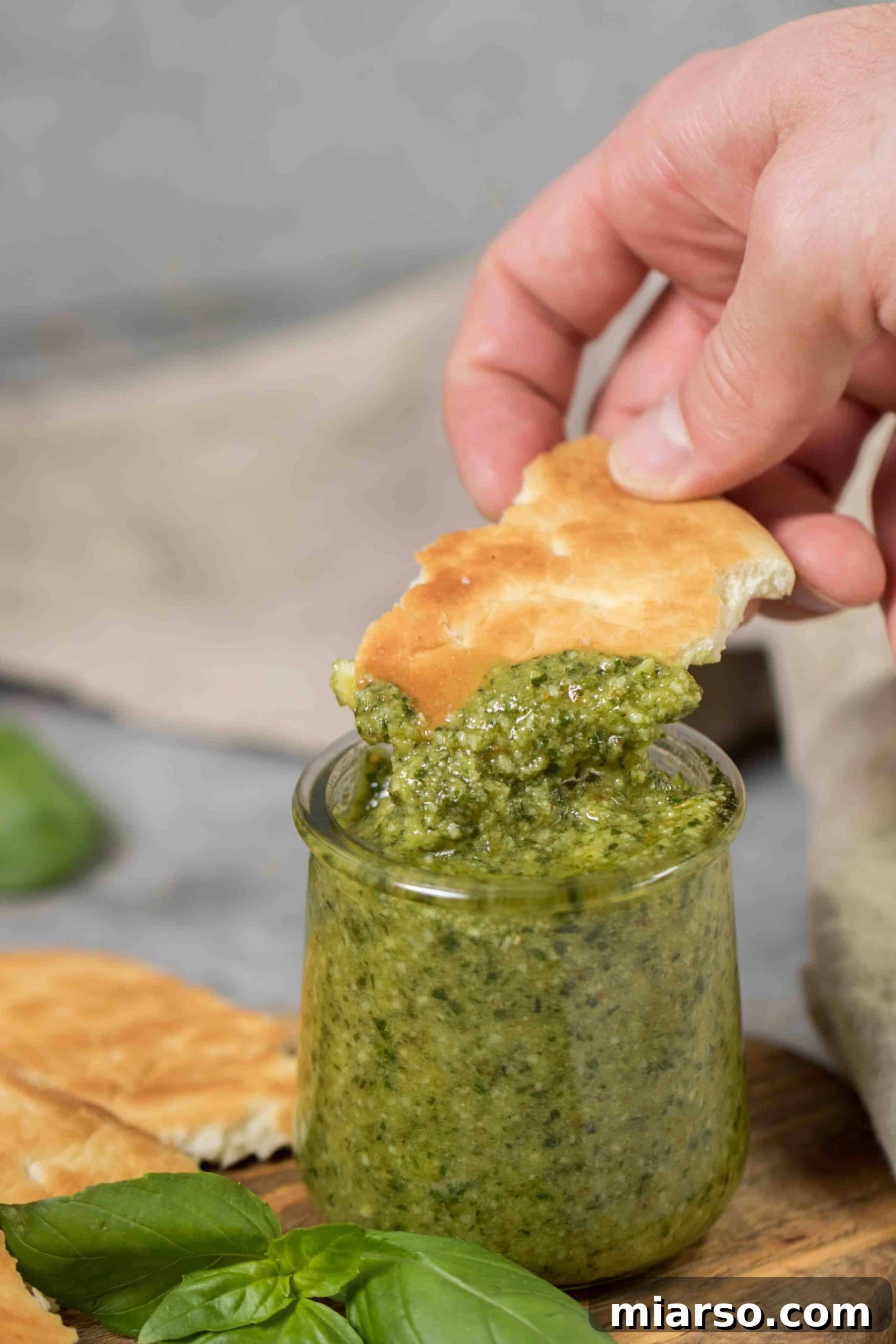 Effortless Homemade Pesto Perfection 8 Flat bread dipped in fresh pesto sauce, highlighting its texture and color.