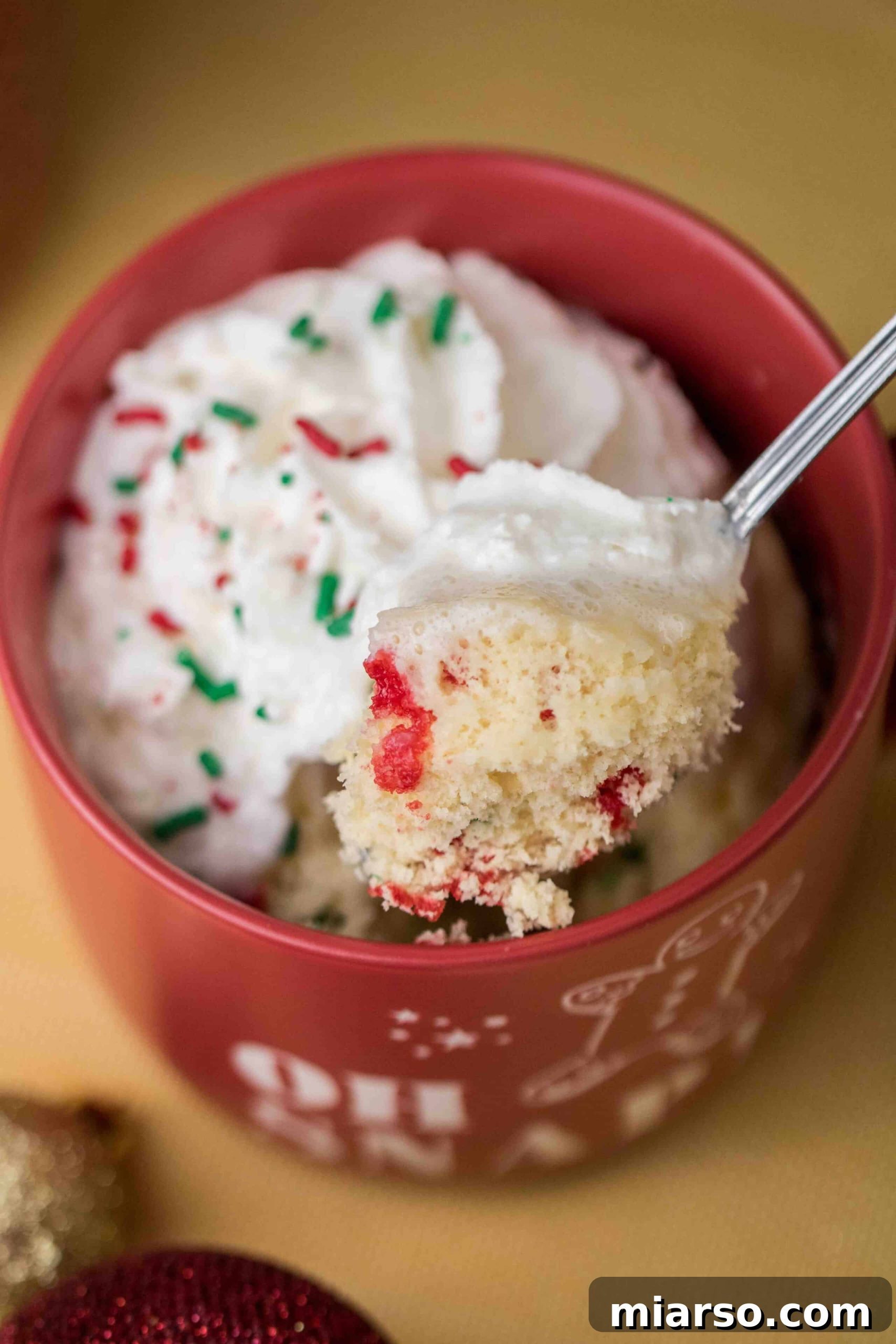 Close-up of a Christmas mug cake interior, showing fluffy texture and colorful sprinkles.