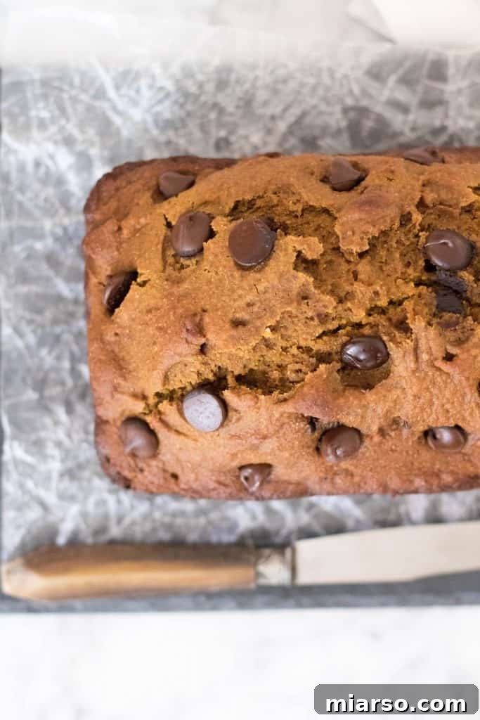A whole loaf of healthy pumpkin bread on a cutting board, ready to be sliced and served.