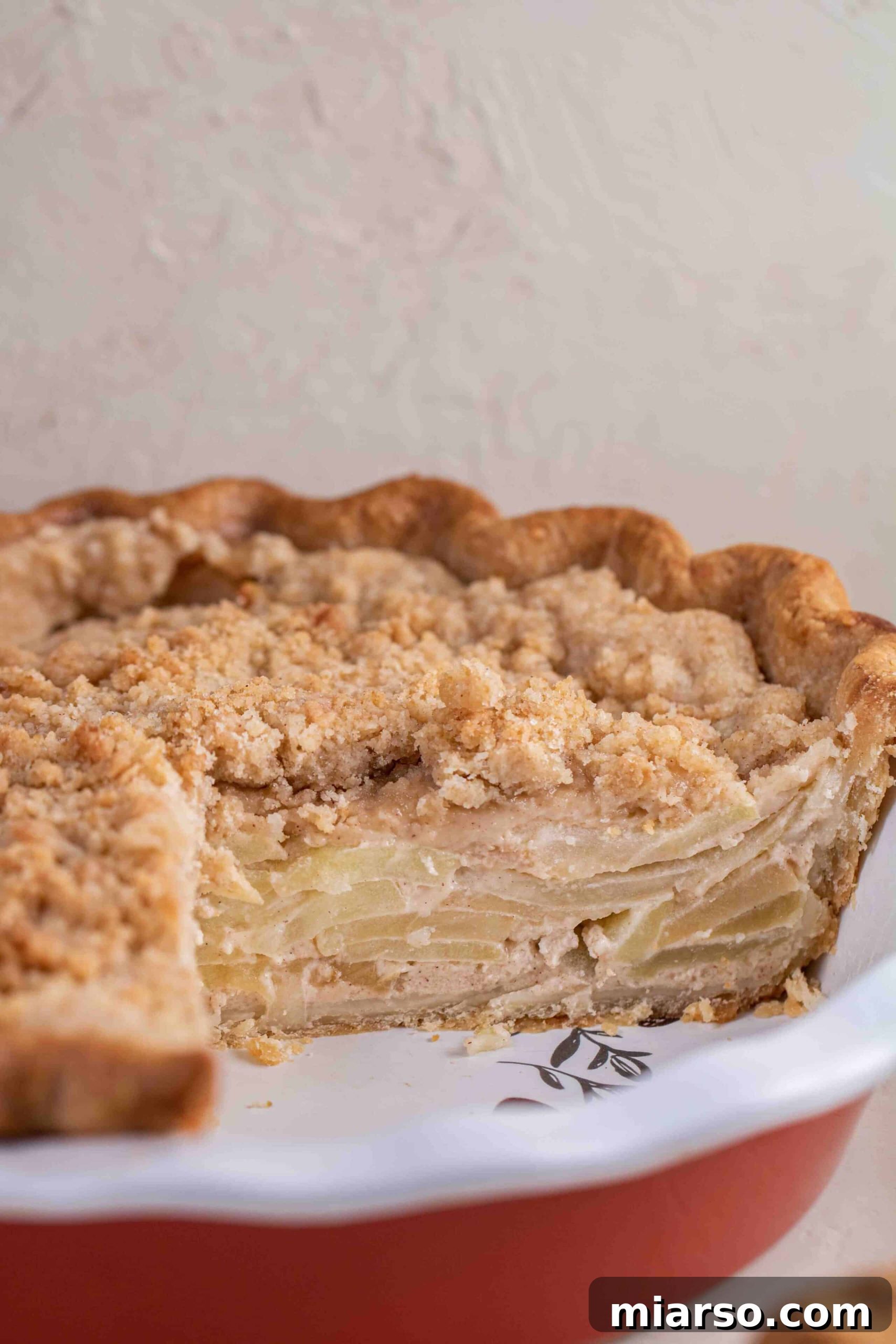 Full apple pie, sliced, showing the interior cooked apple slices and the golden-brown crumb topping.