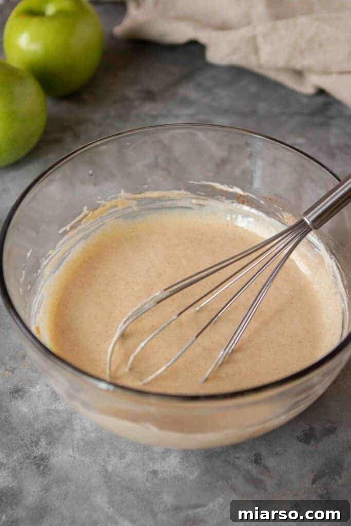 Apple pie filling ingredients being mixed in a bowl.