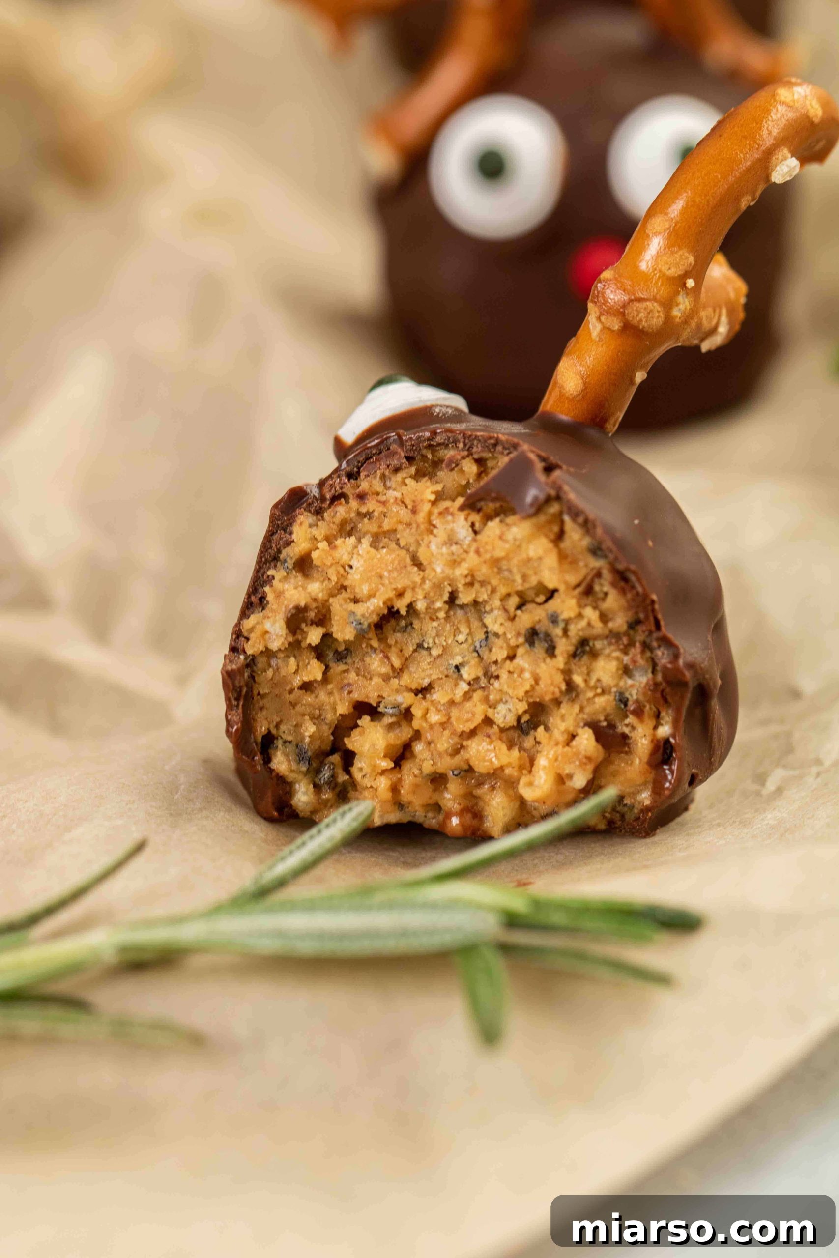 Close-up shot showing the crunchy texture inside a halved reindeer peanut butter ball with rice krispies.