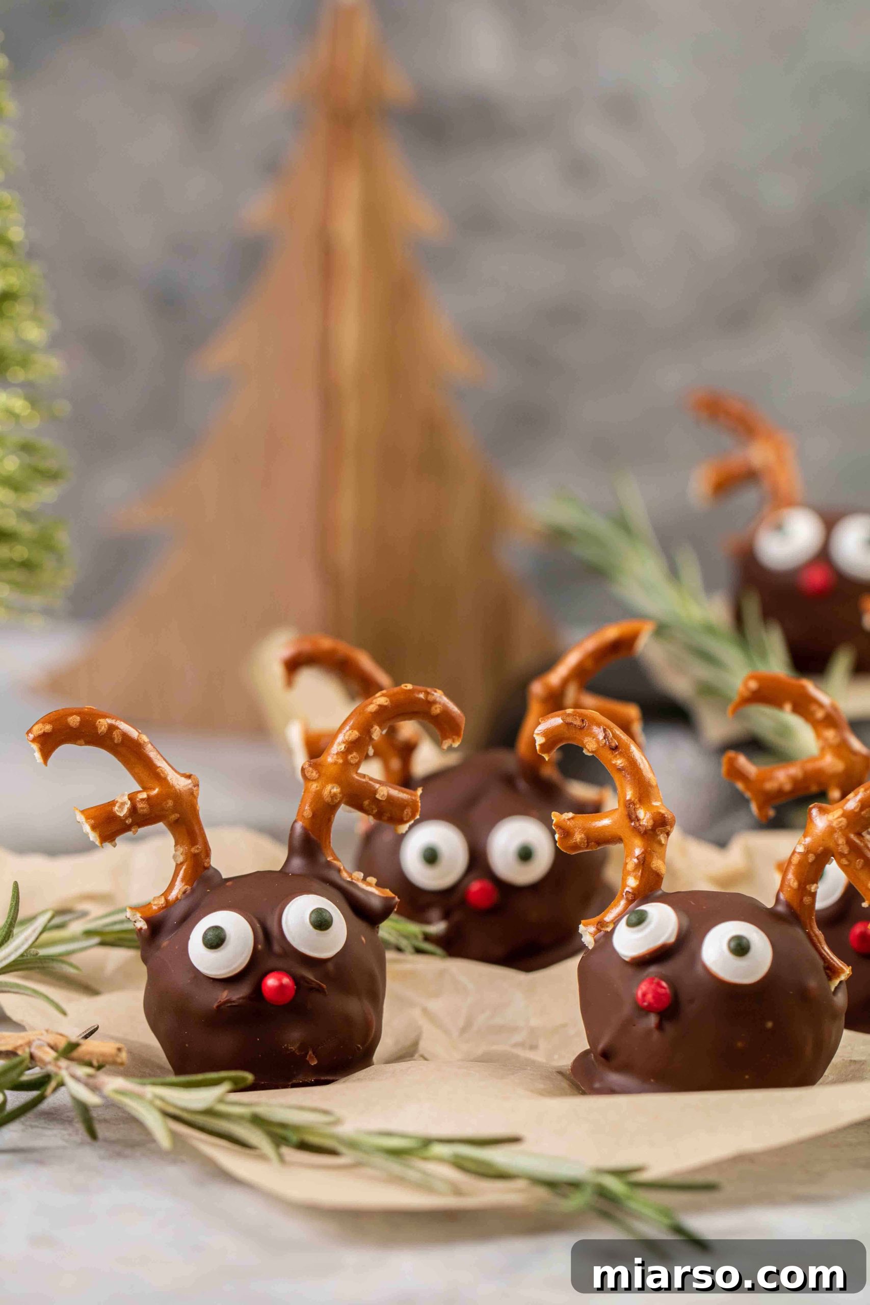 Straight shot of three finished reindeer peanut butter balls, showcasing their cute decorations.