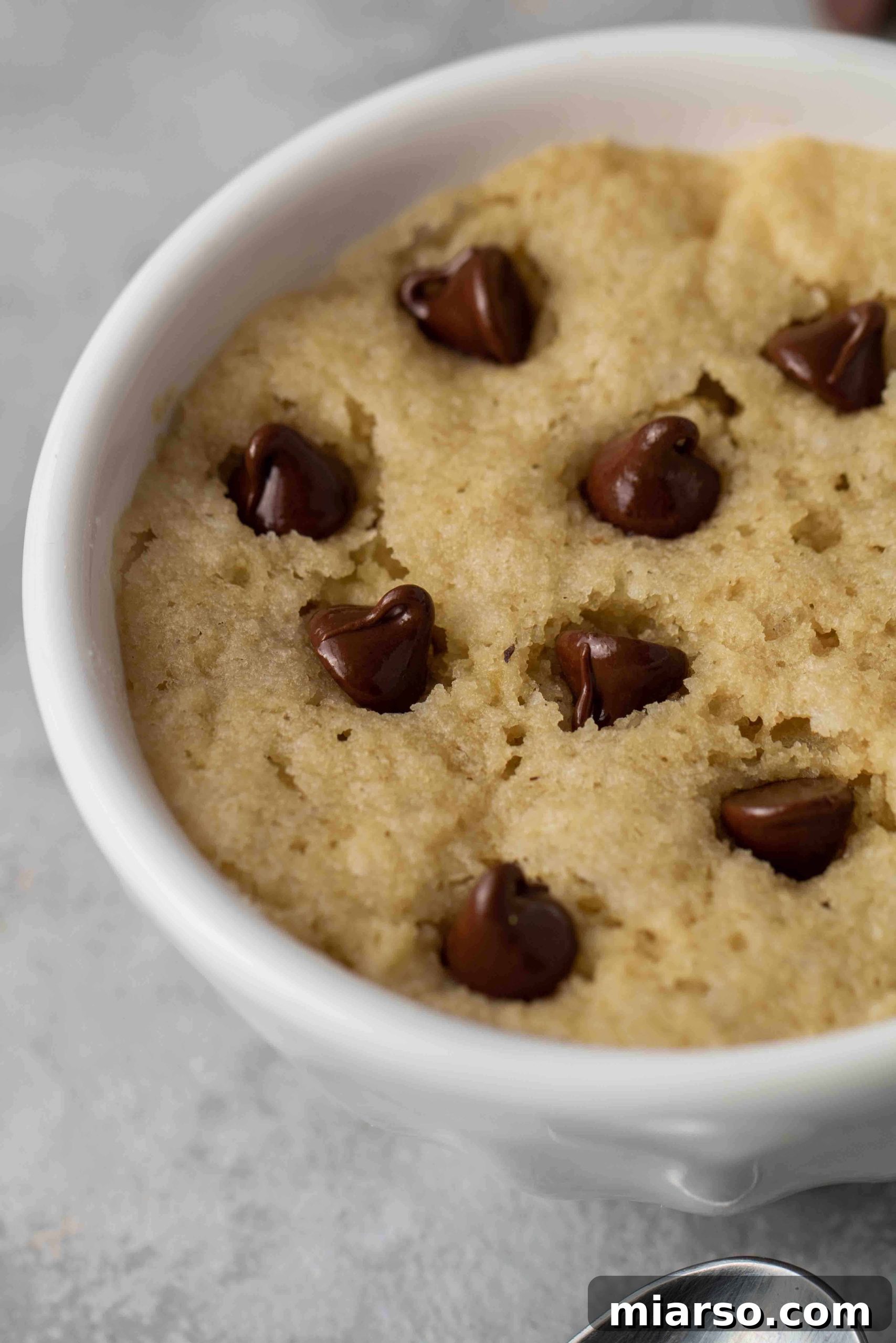 A golden-brown vegan chocolate chip mug cookie with melted chocolate, ready to eat.