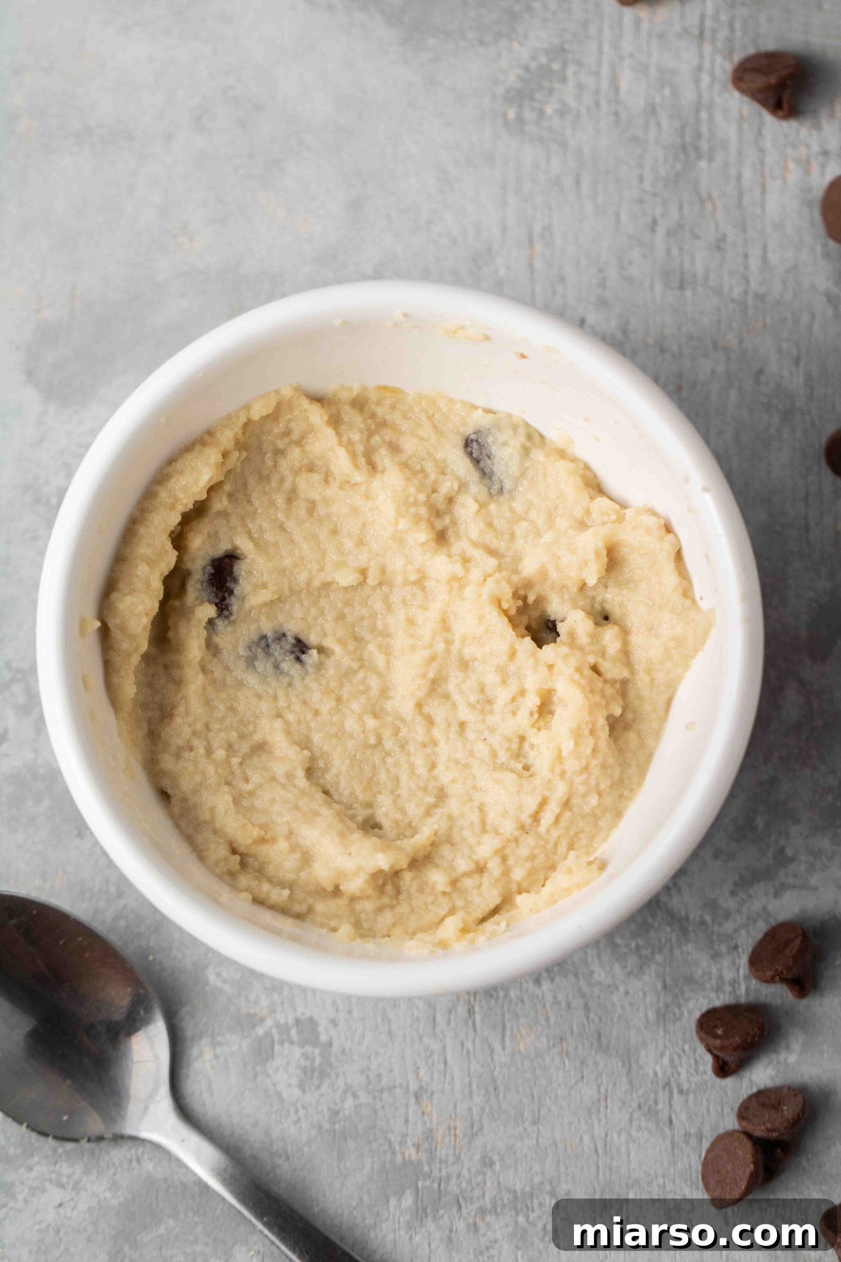 Freshly microwaved vegan chocolate chip mug cookie, topped with extra chocolate chips.