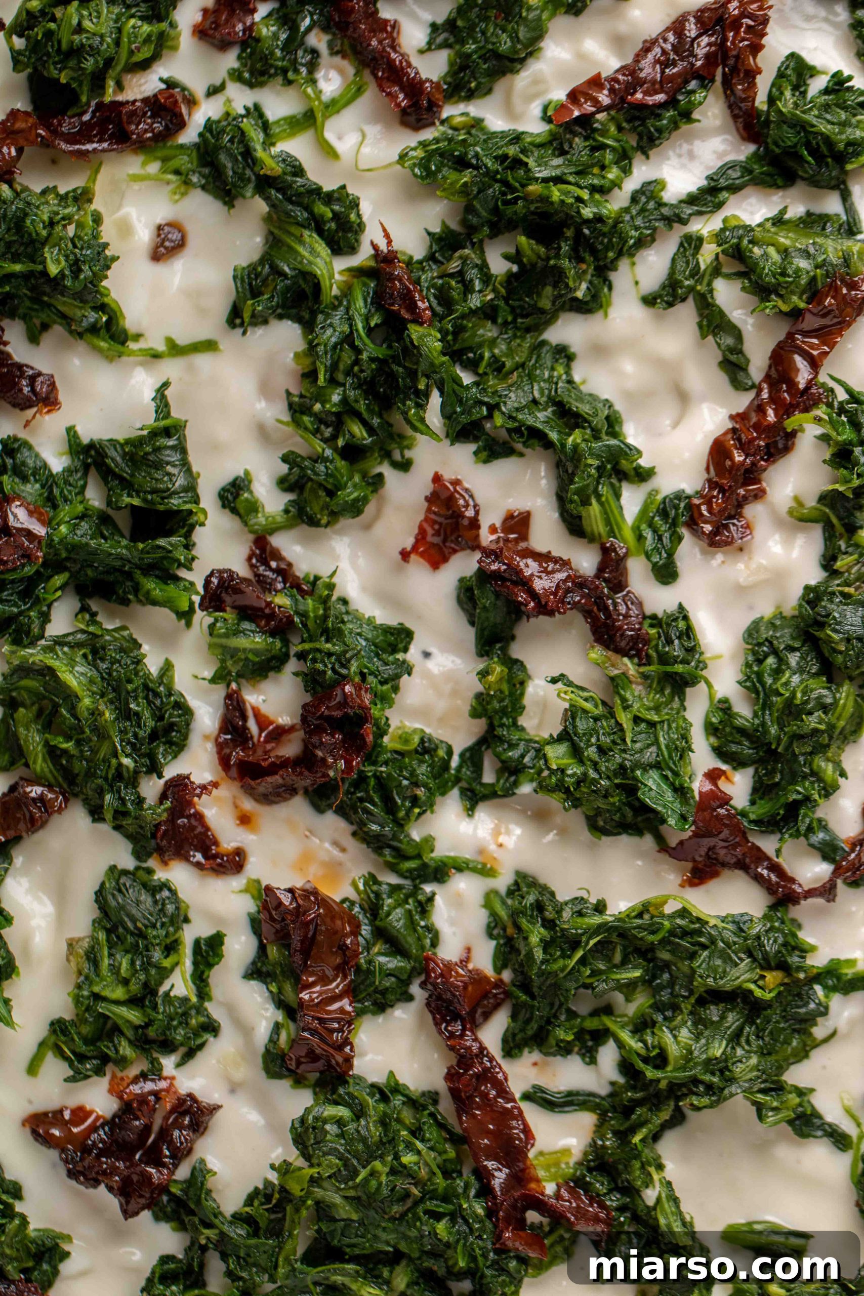 Close up of Spinach and sun dried tomato white pizza recipe, vibrant colors