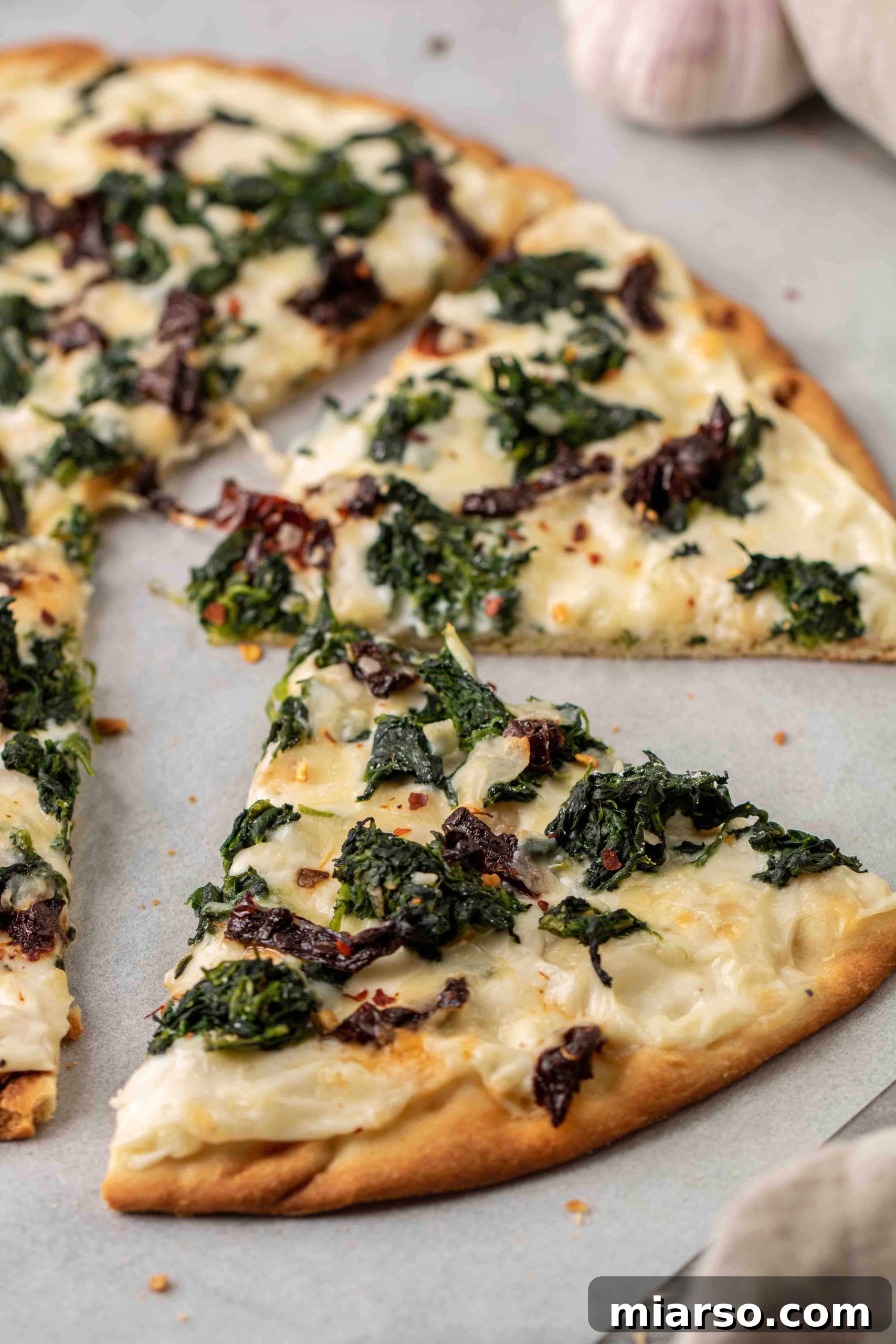 Slicing a delicious white spinach pizza with a pizza cutter