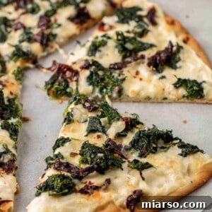 Baked slice of spinach pizza with white sauce, perfect golden crust