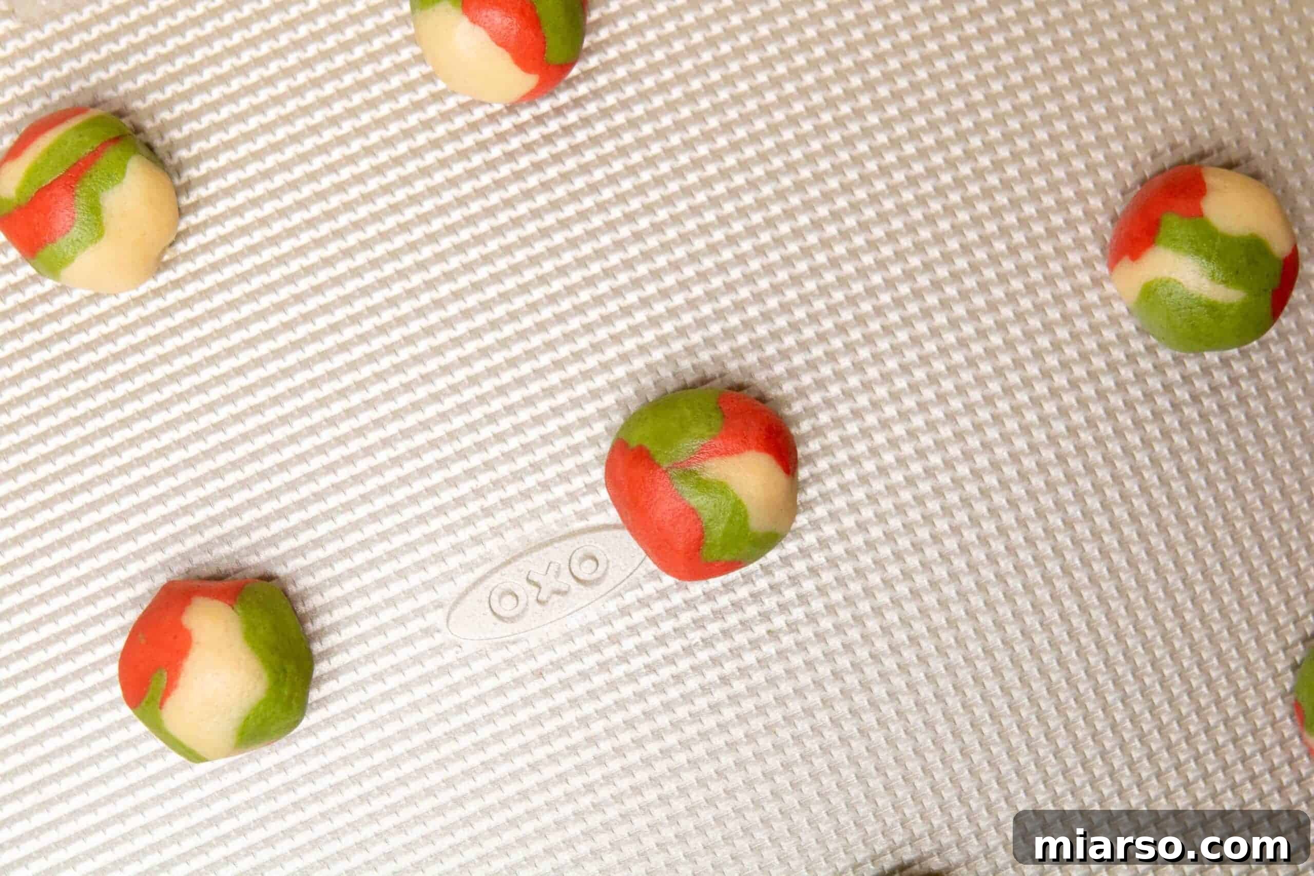 Marbled cookie dough balls arranged on a parchment-lined baking sheet