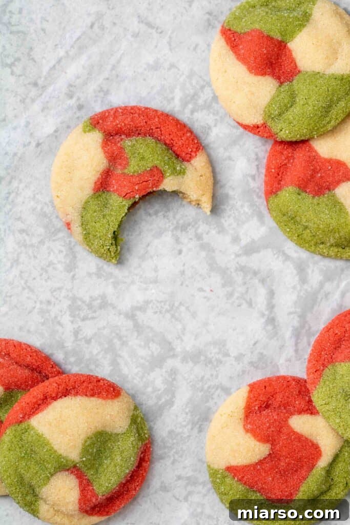 Overhead shot of freshly baked Christmas sugar cookies, with one cookie showing a bite taken out, revealing the soft interior.