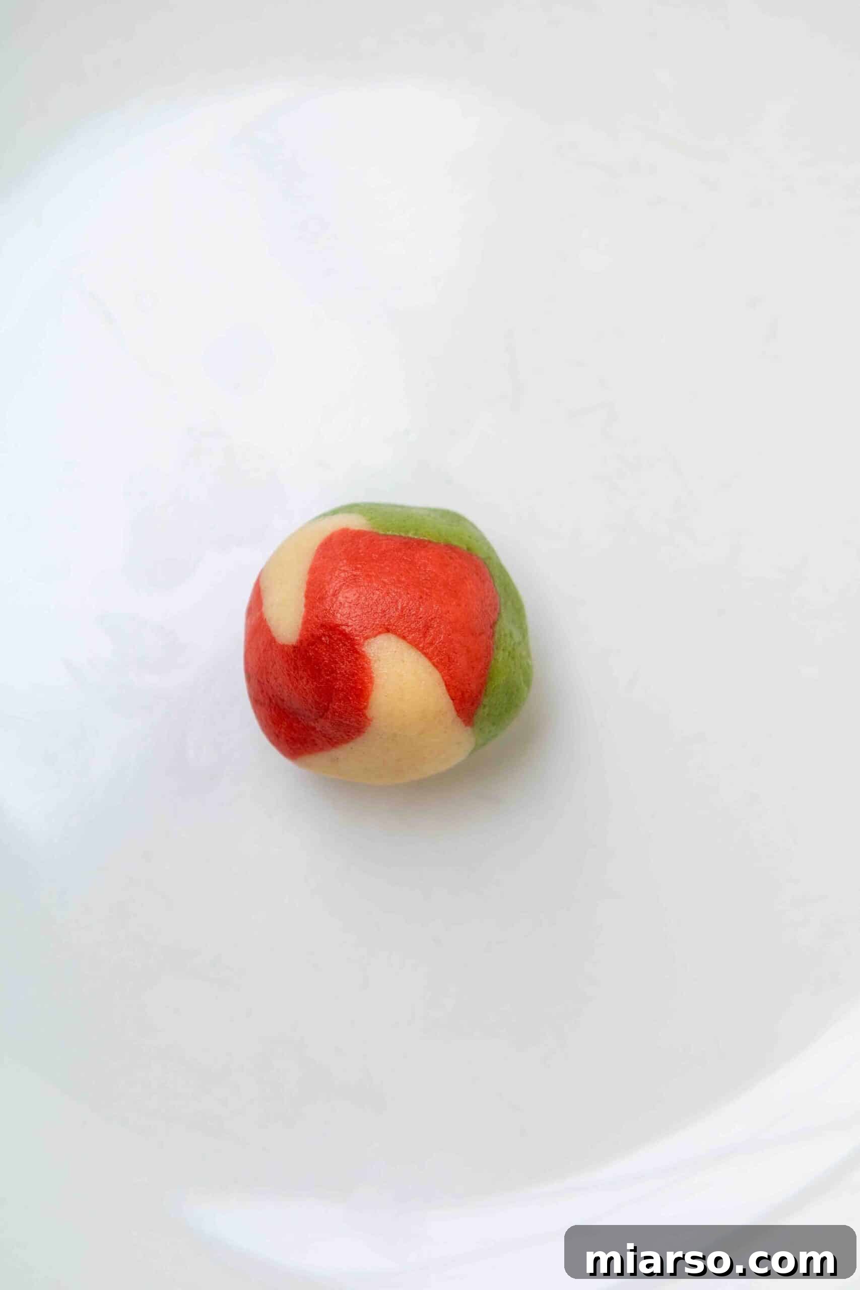 A gently rolled marbled cookie dough ball showing distinct color swirls
