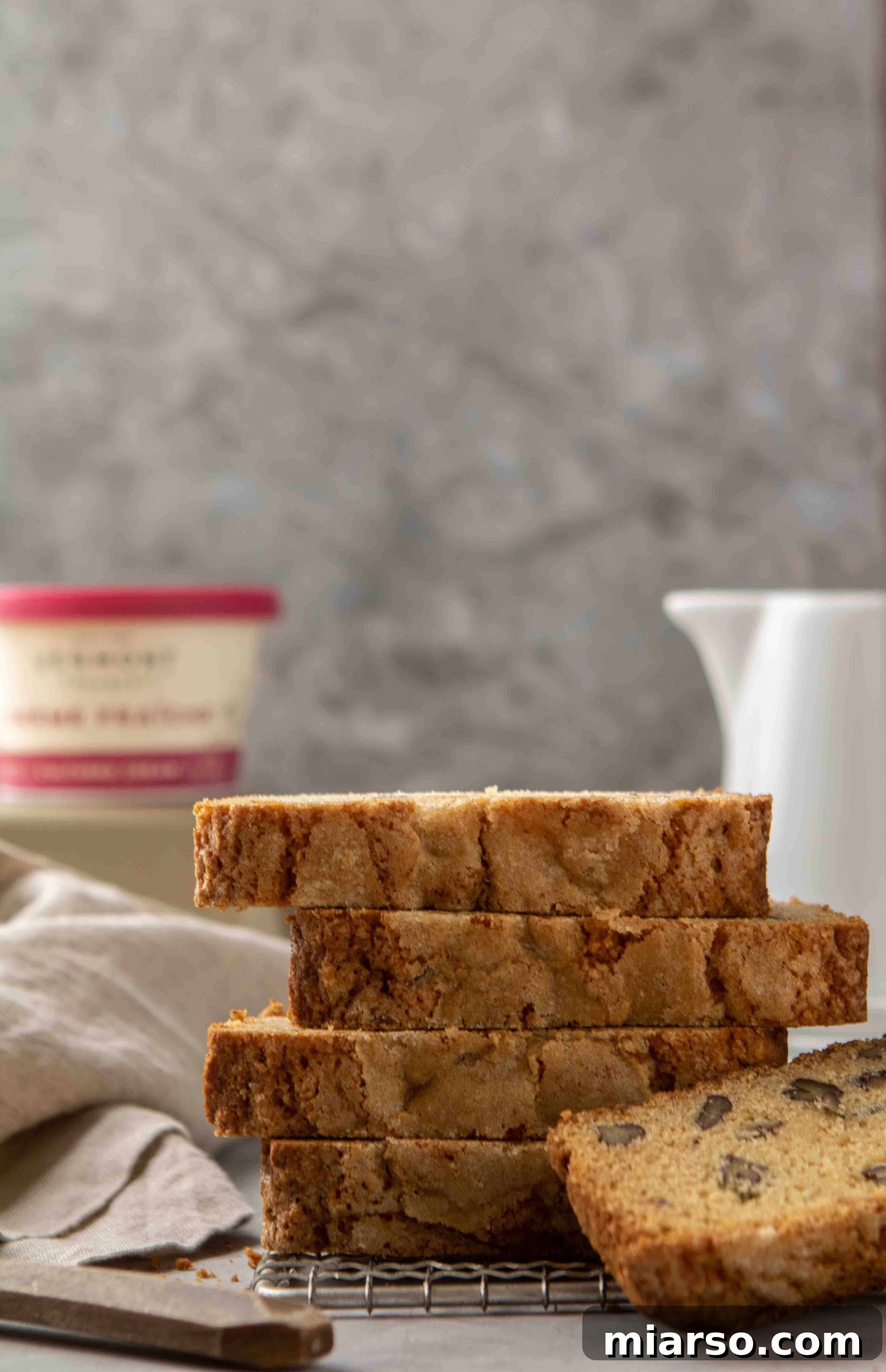 Straight on shot of maple pecan bread slices stacked on top of each other, showcasing the moist interior