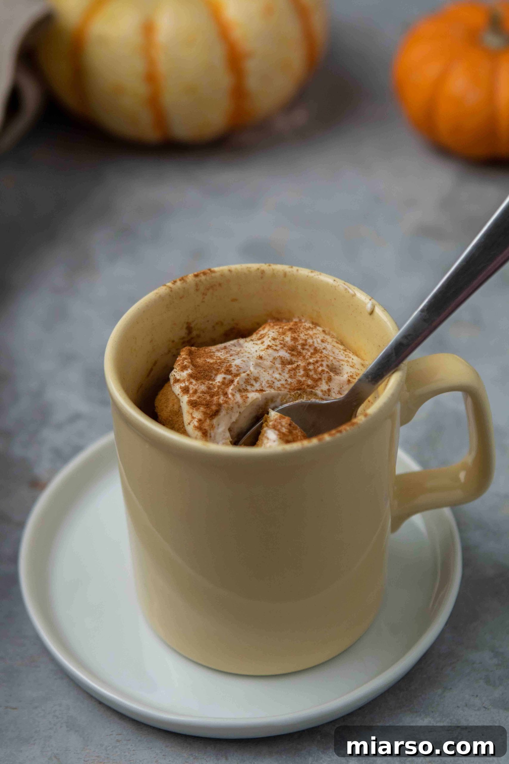 A close-up of the smooth, golden pumpkin mug cake batter in a yellow mug after all ingredients have been mixed.