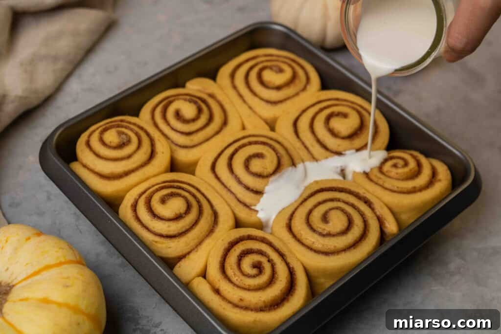 Pouring heavy cream over cinnamon rolls before baking