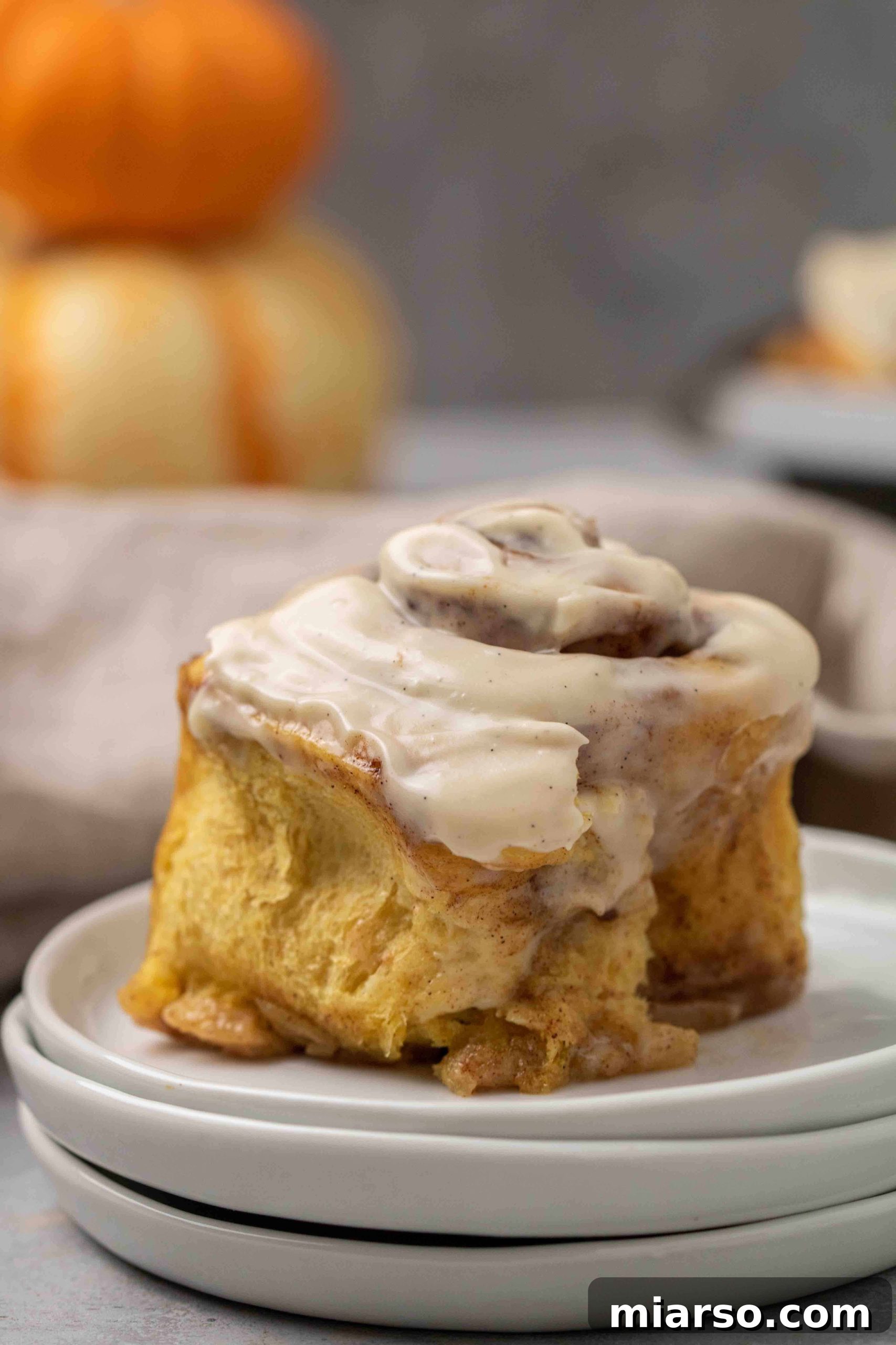 A close-up of a pumpkin cinnamon roll with frosting