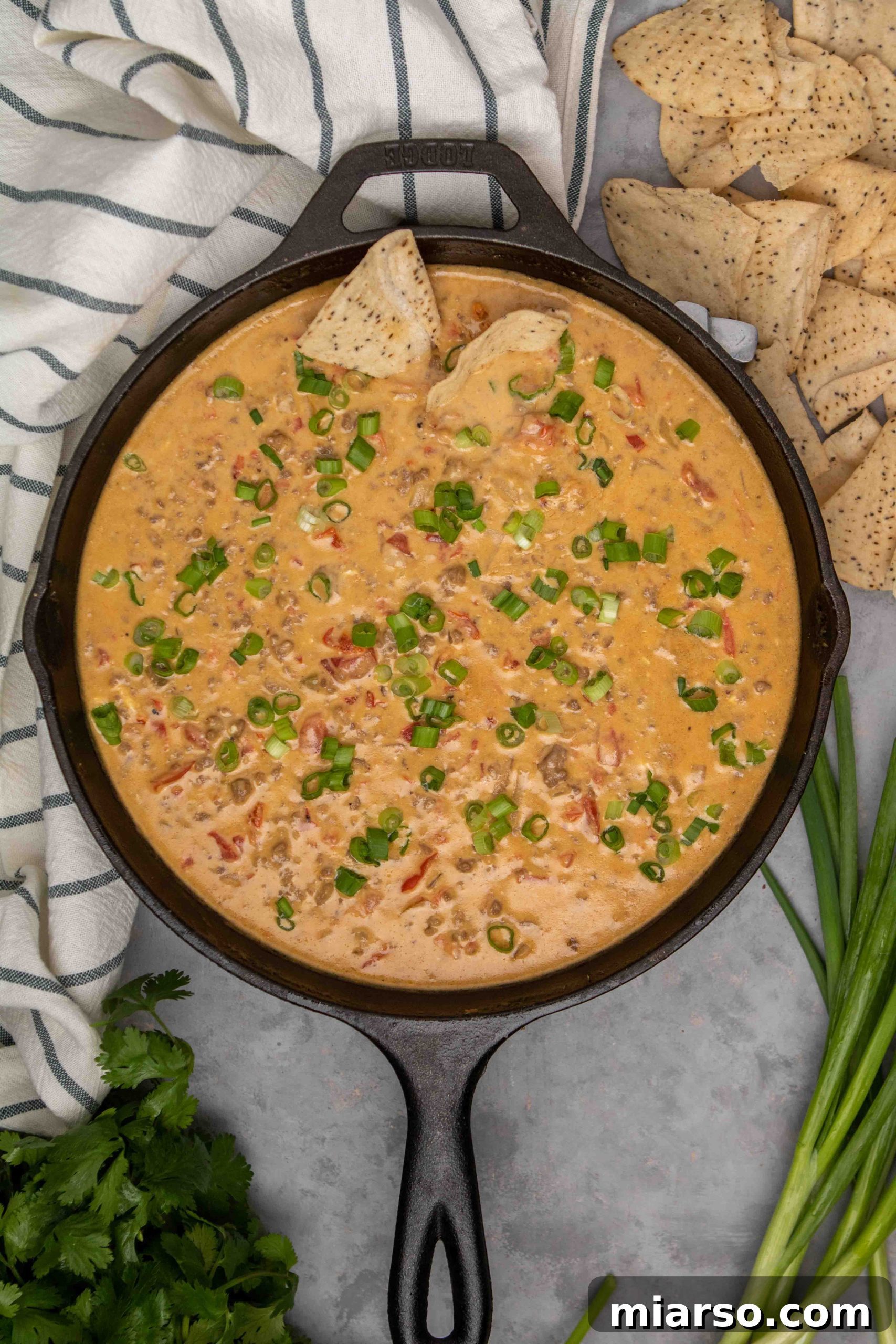 Close-up shot of Rotel dip being scooped with a chip, highlighting its creamy texture.