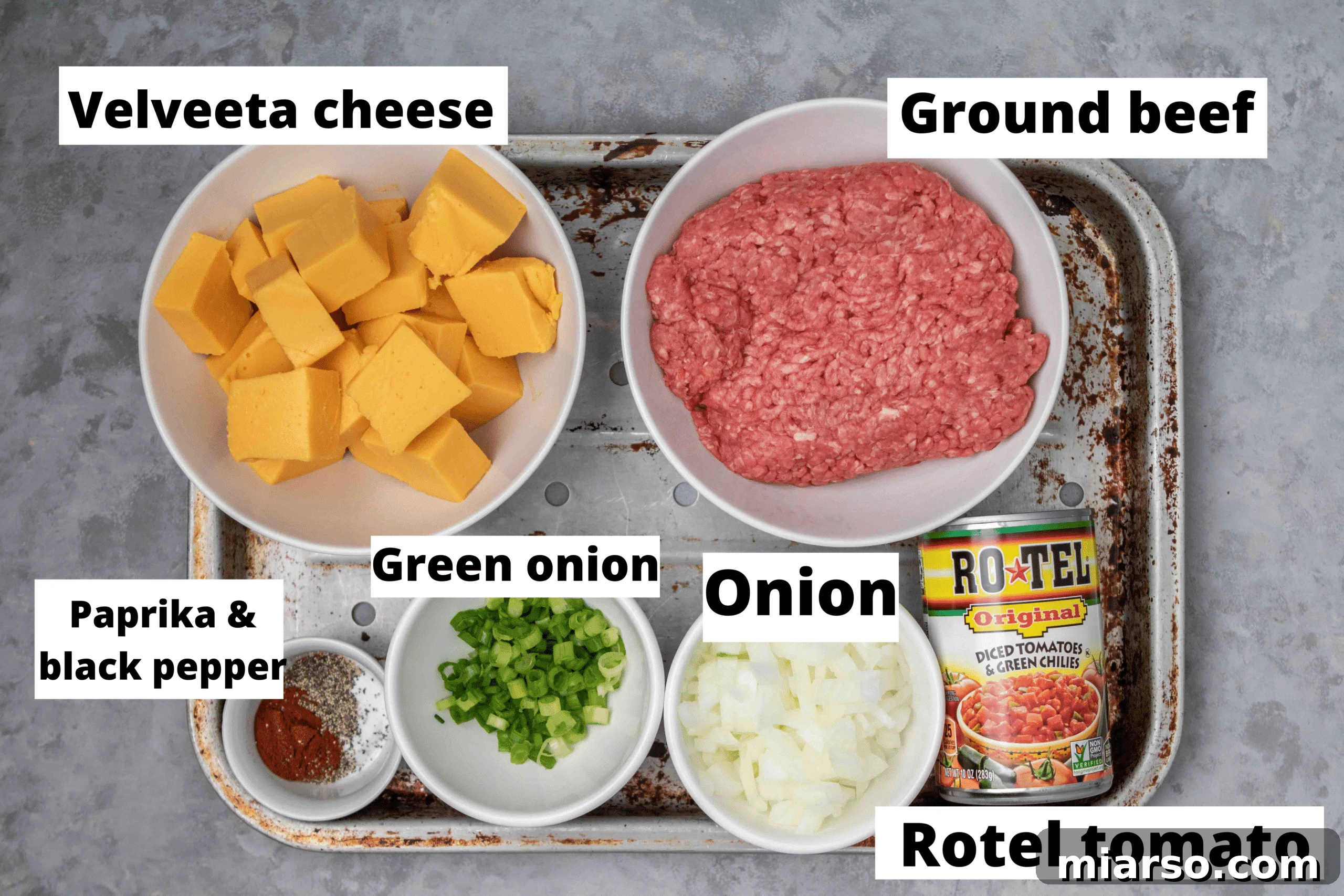 A flat lay of all the fresh and canned ingredients needed for making Rotel dip, including Velveeta, Rotel tomatoes, ground beef, and spices.