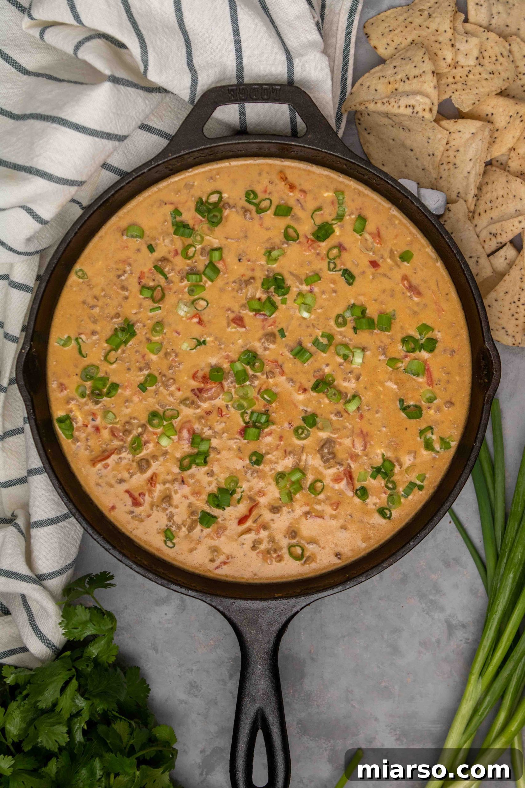 Step-by-step image showing Rotel tomatoes, Velveeta, and cream cheese melting into the browned ground beef mixture in a skillet.