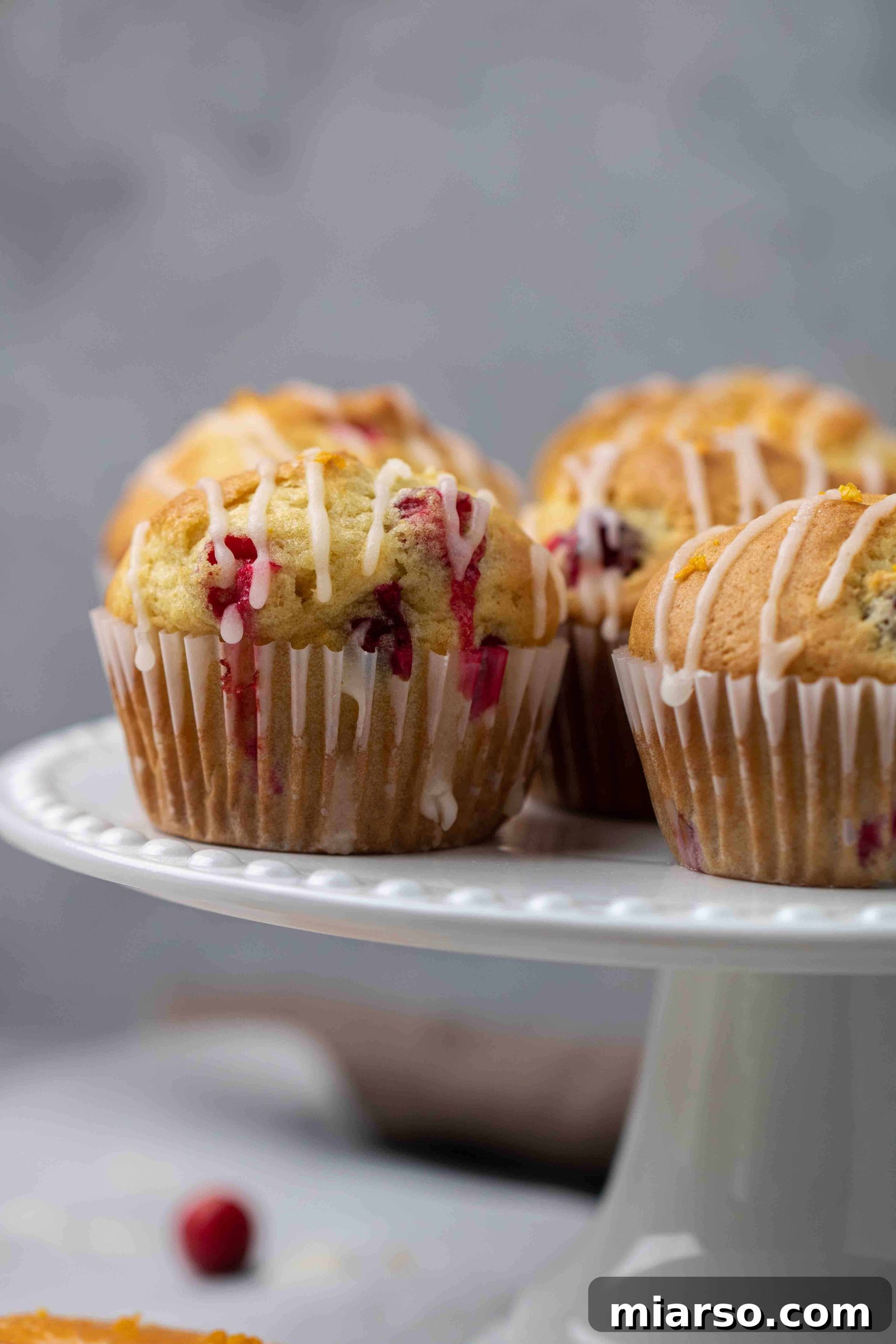 Bakery style cranberry orange muffins on a cake stand