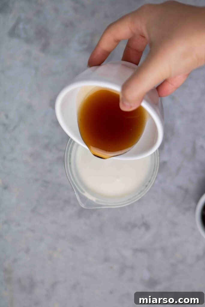Starbucks Velvety Vanilla Cold Brew 9 Maple syrup being poured into a bowl with half and half, starting the sweet cream mixture.