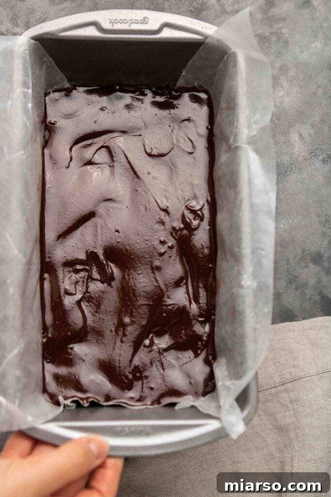 Step-by-step guide: Spreading the hazelnut base evenly into a parchment-lined loaf pan.