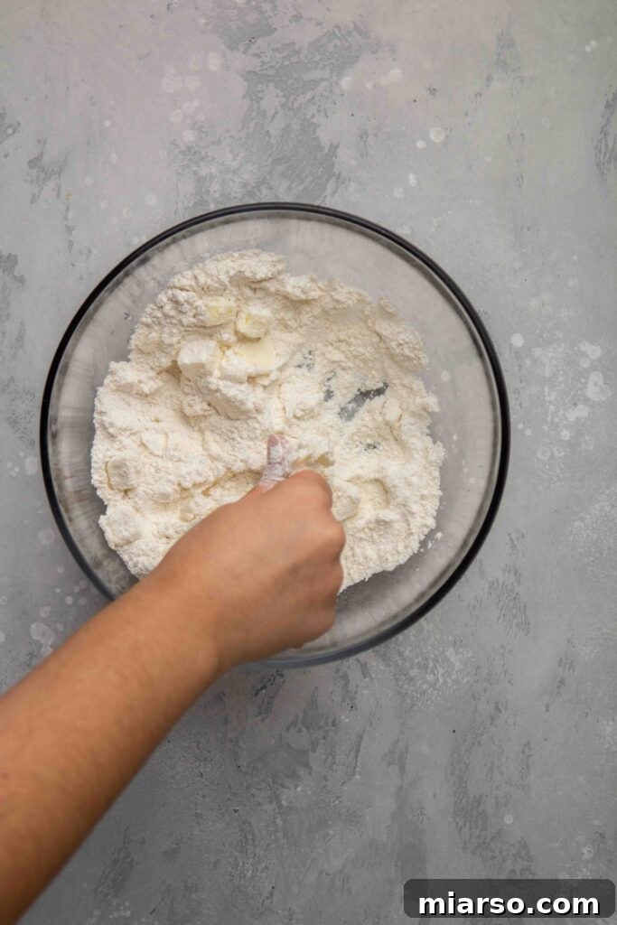 Image showing cold cubed butter being added to the flour mixture.