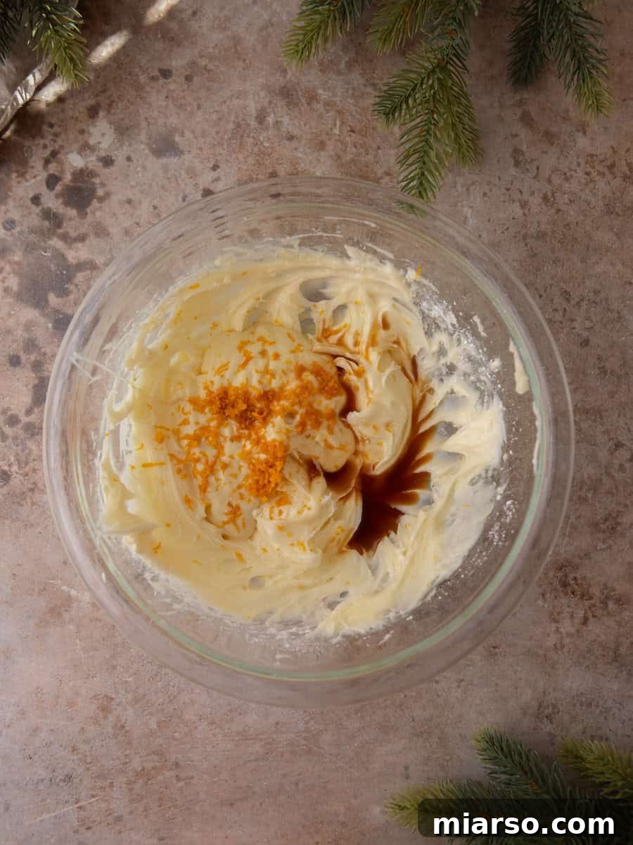 Cream cheese frosting in a bowl with fresh orange zest and vanilla added.
