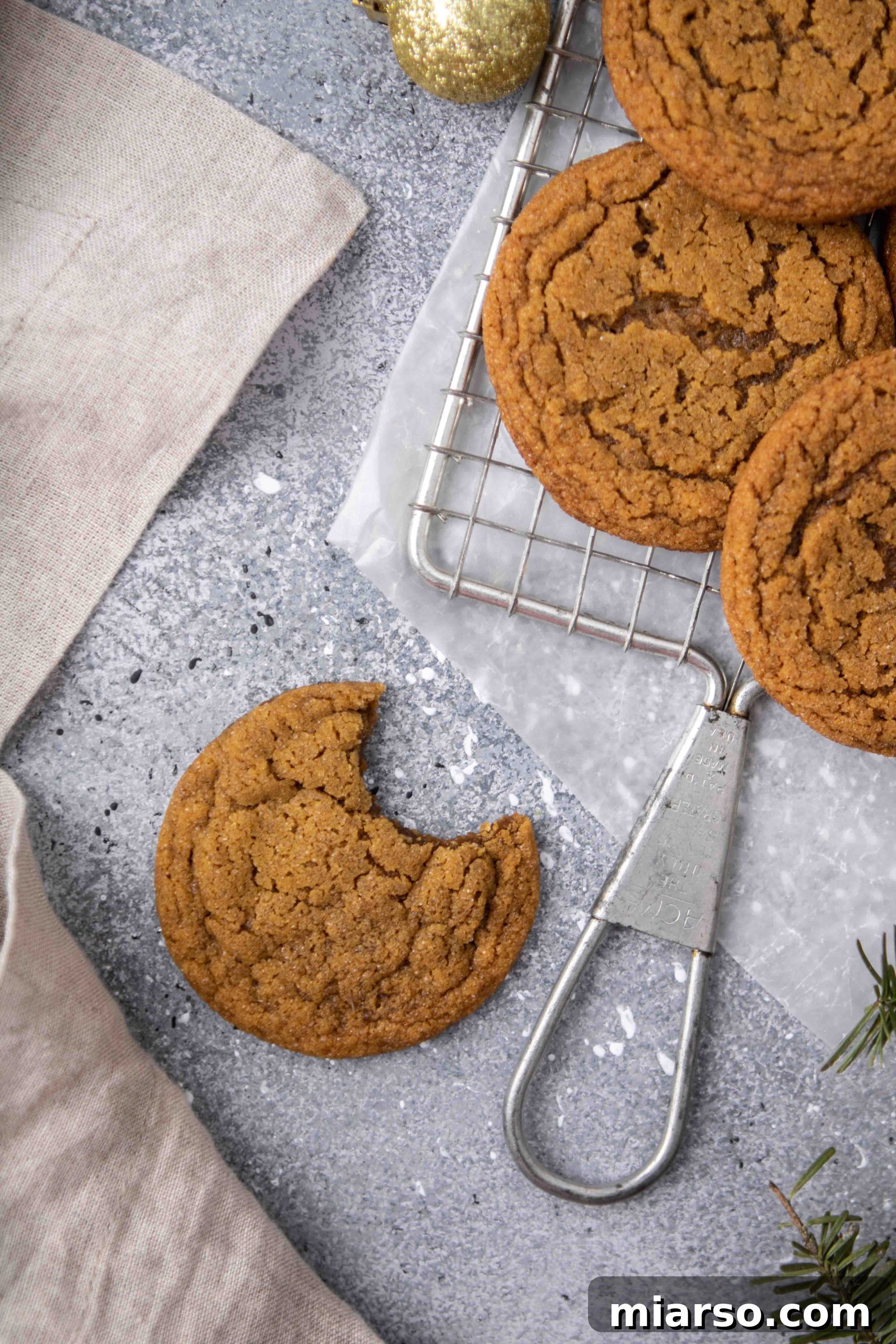 Perfectly Soft and Chewy Ginger Molasses Cookies 17 A plate of ginger molasses cookies with one cookie broken to show its soft interior.