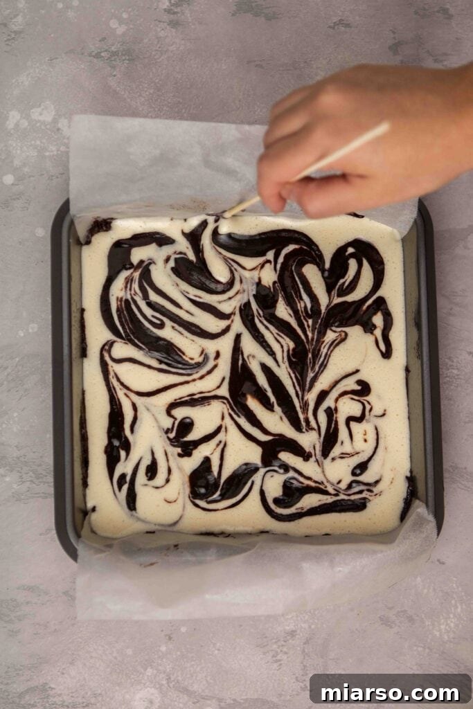 Swirling the brownie batter into the cheesecake batter for a beautiful marble effect