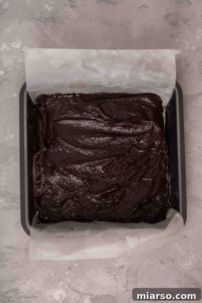 Evenly spreading brownie batter into the prepared baking pan