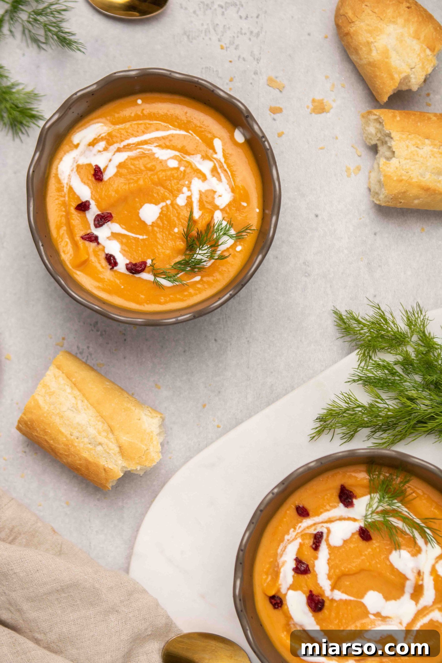 Vibrant orange spiced soup served with crusty baguette bread, inviting diners to dip and enjoy.