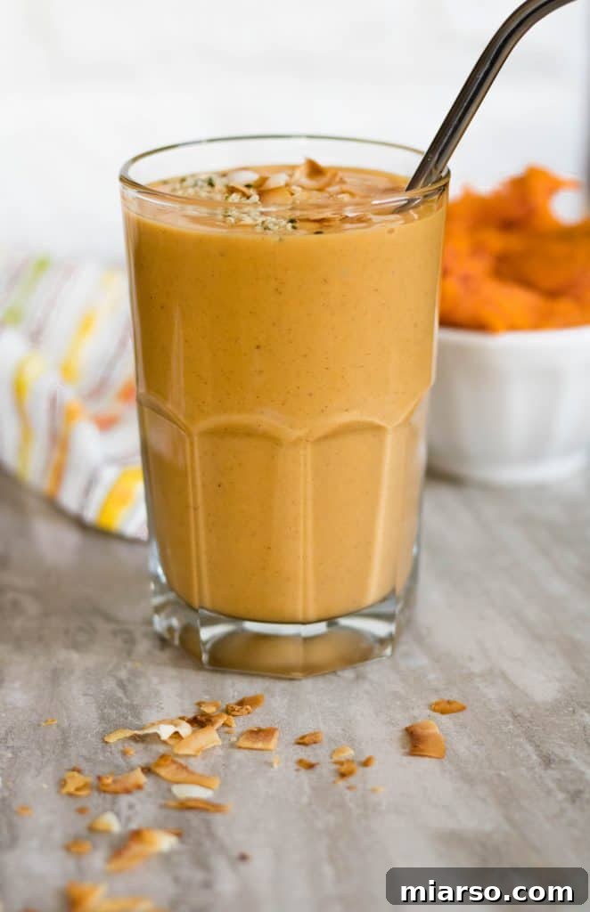 Close-up of a sweet potato smoothie in a glass with a straw