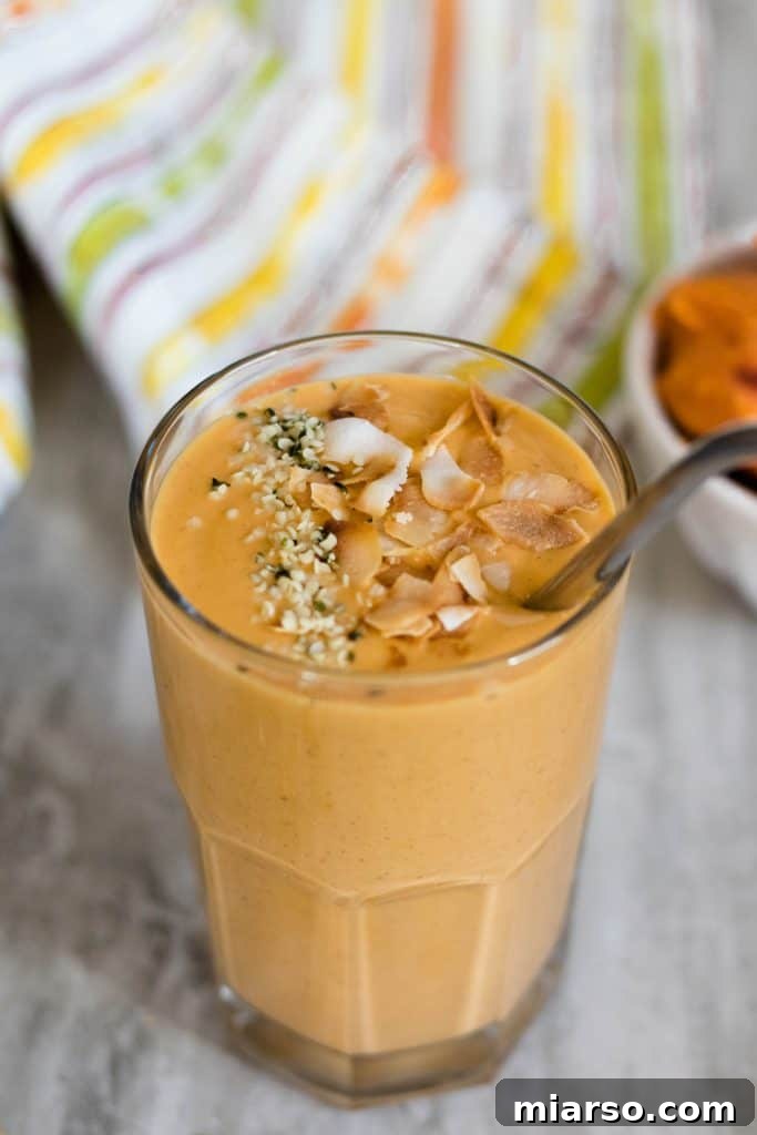 Sweet potato smoothie in a tall glass with a metal straw