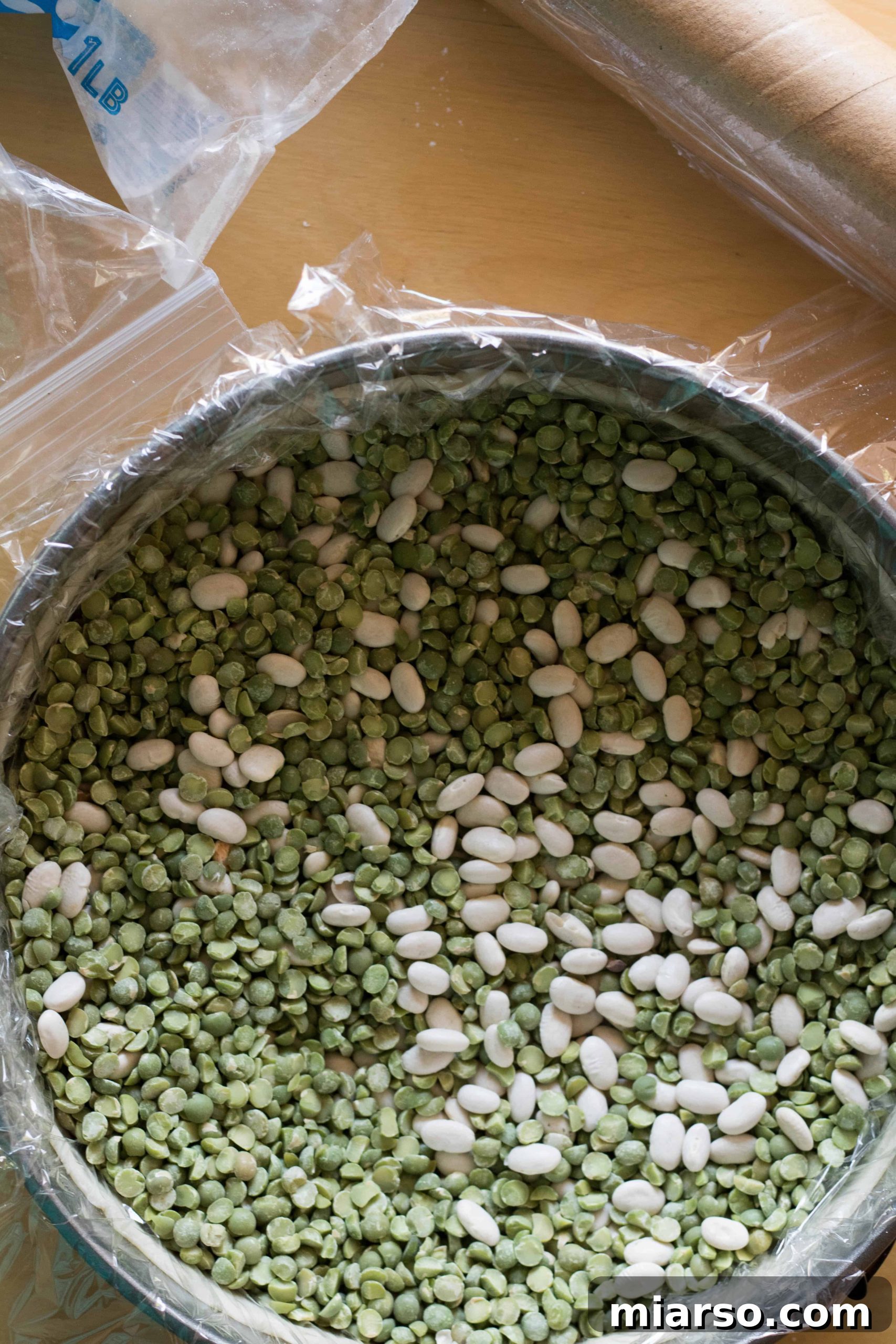 Another view of pie crust being lined with plastic wrap and dry beans.