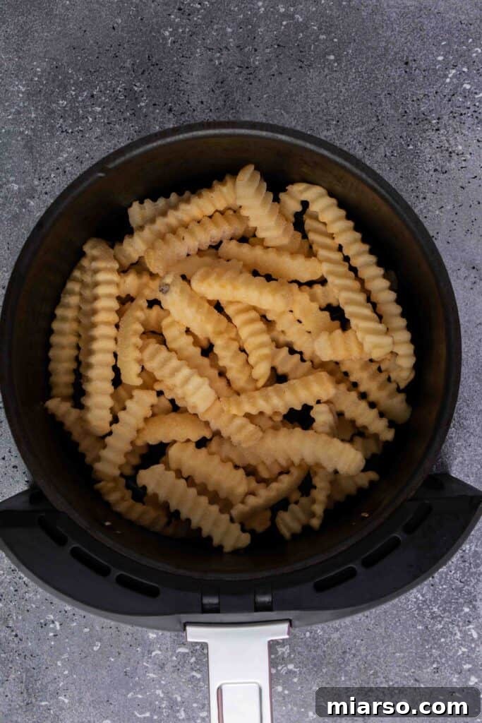 Step by step image showing frozen french fries poured into air fryer basket