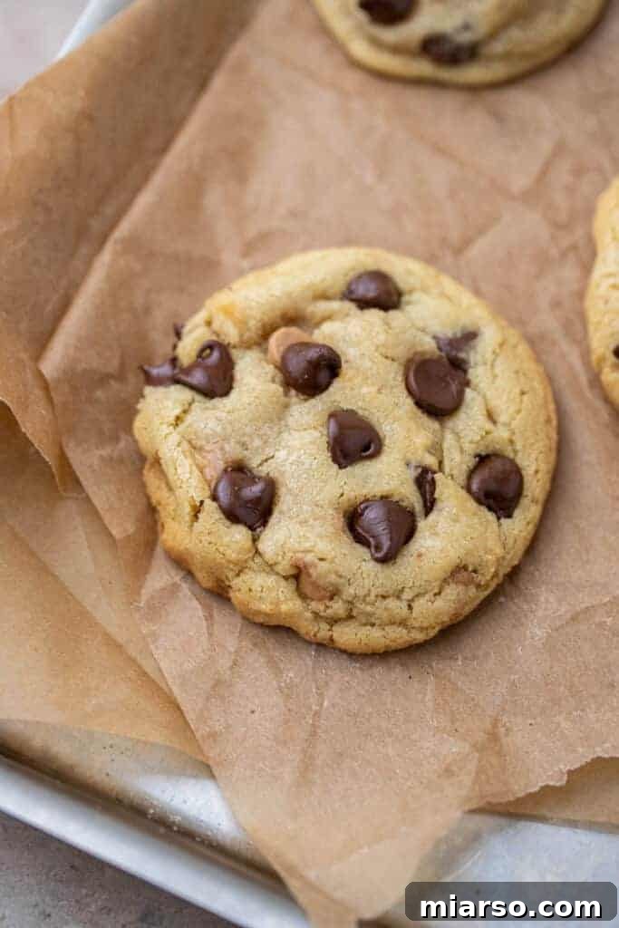 Overhead shot of freshly baked small batch chocolate chip cookies on a parchment-lined baking sheet, glistening with melted chocolate chips.