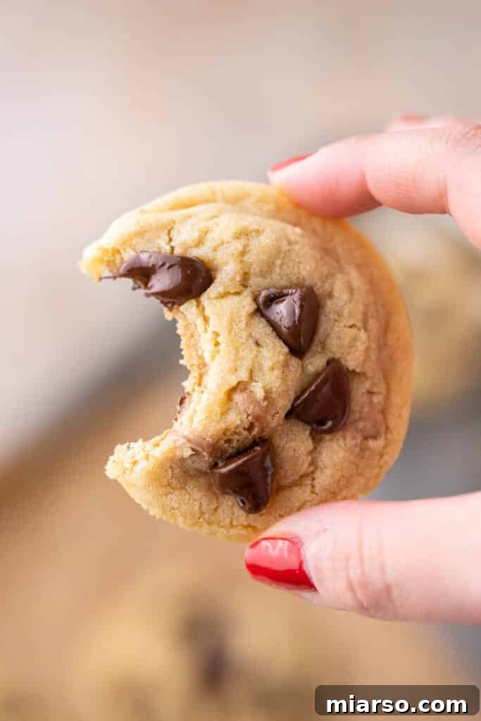 Small batch chocolate chip cookie with a perfect bite taken out, revealing its soft and chewy interior.