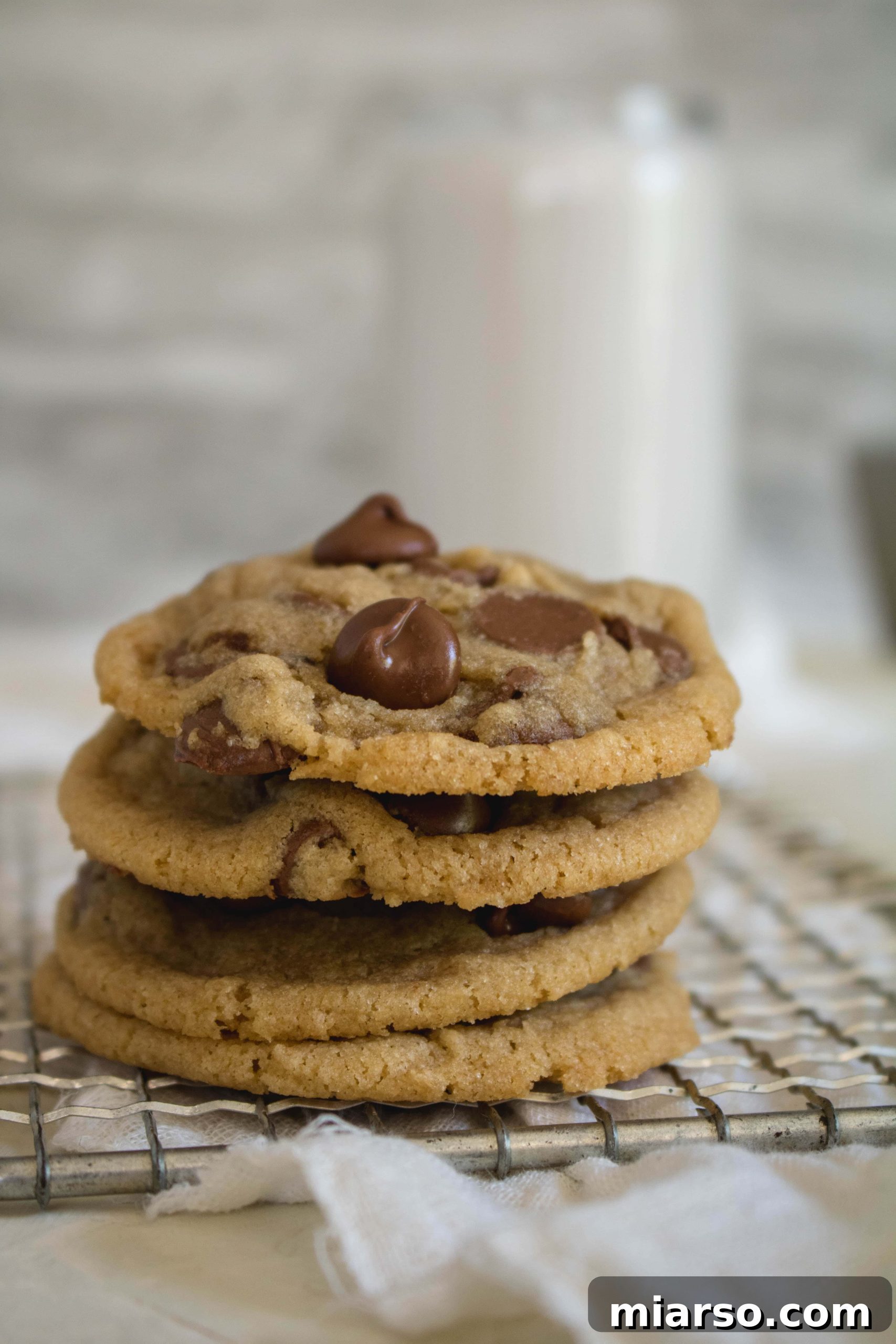 A close-up of a stack of fresh, soft chocolate chip cookies, highlighting their golden-brown edges and molten chocolate centers.