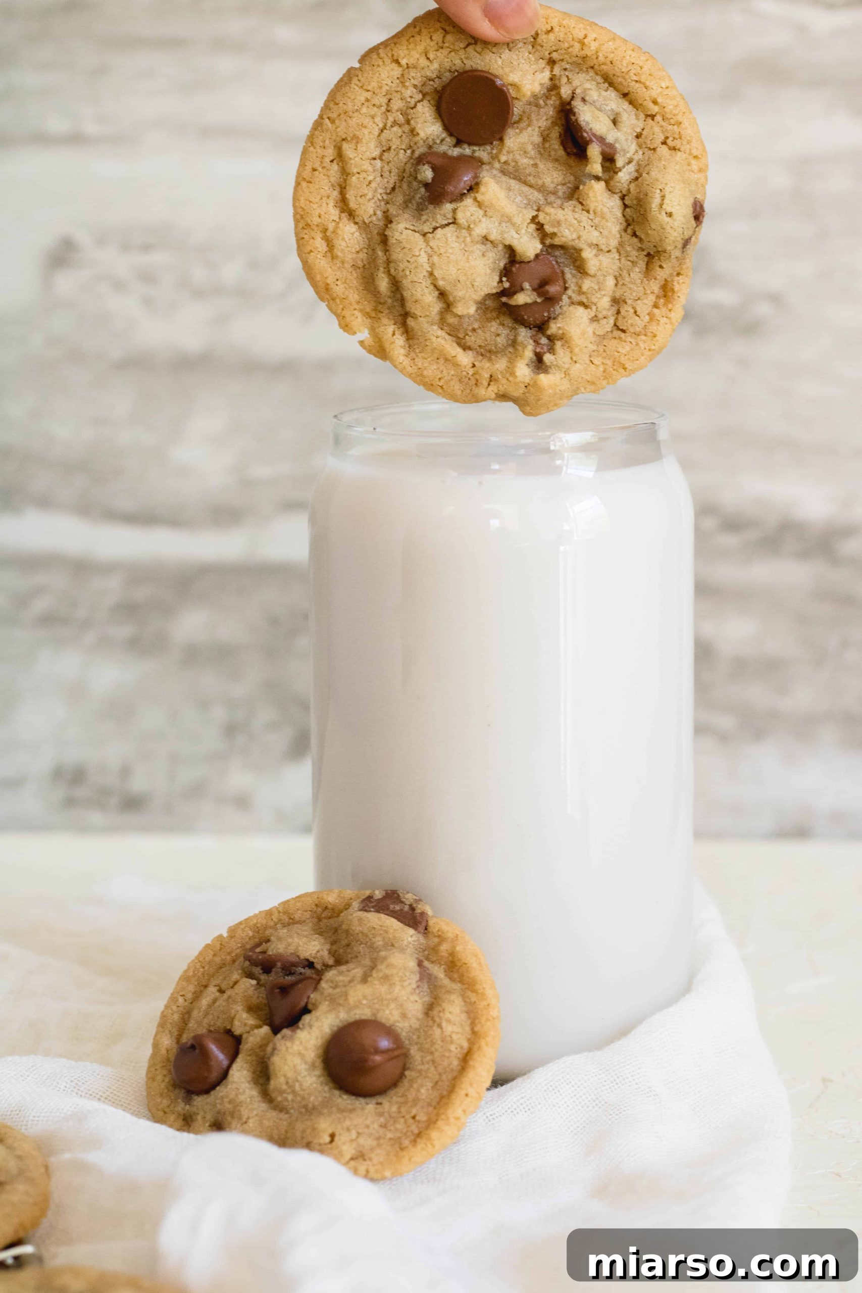Close-up of a small batch chocolate chip cookie with a glass of milk, emphasizing its perfect texture.