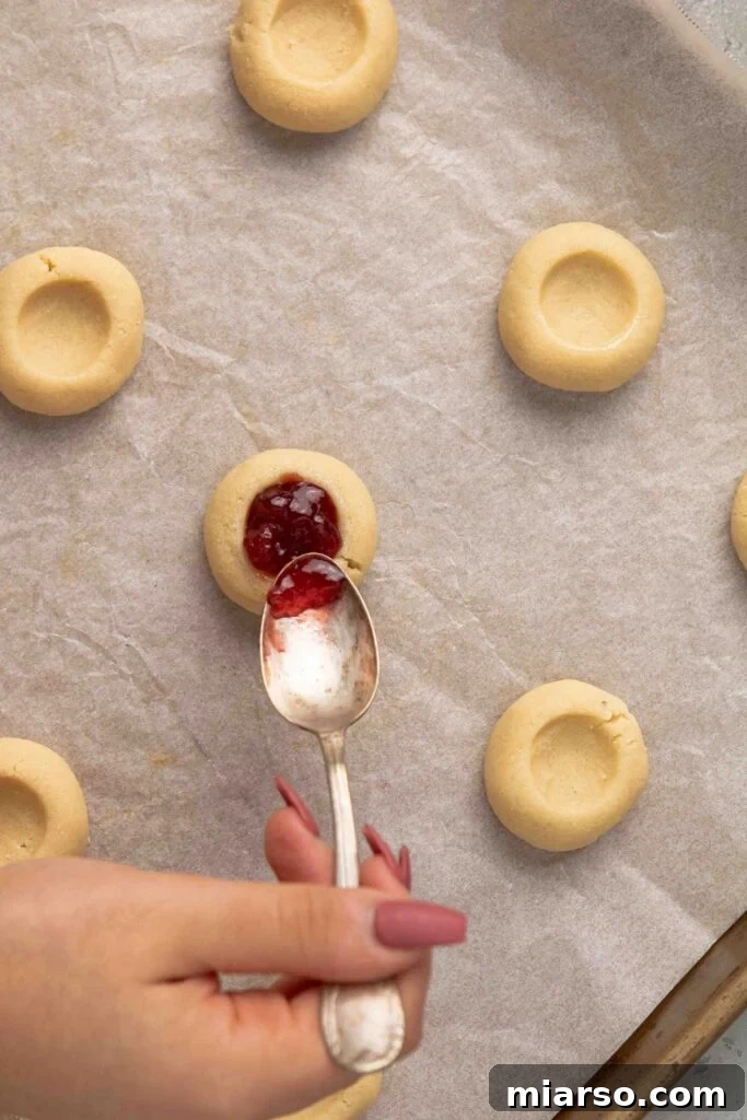 Jam-Kissed Almond Thumbprint Cookies 11 Step 5: Filling the thumbprint cookies with sweet jam.