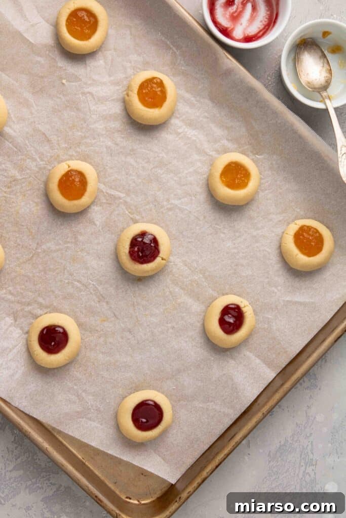 Jam-Kissed Almond Thumbprint Cookies 12 Step 6: Baking the jam-filled cookies to golden perfection in the oven.