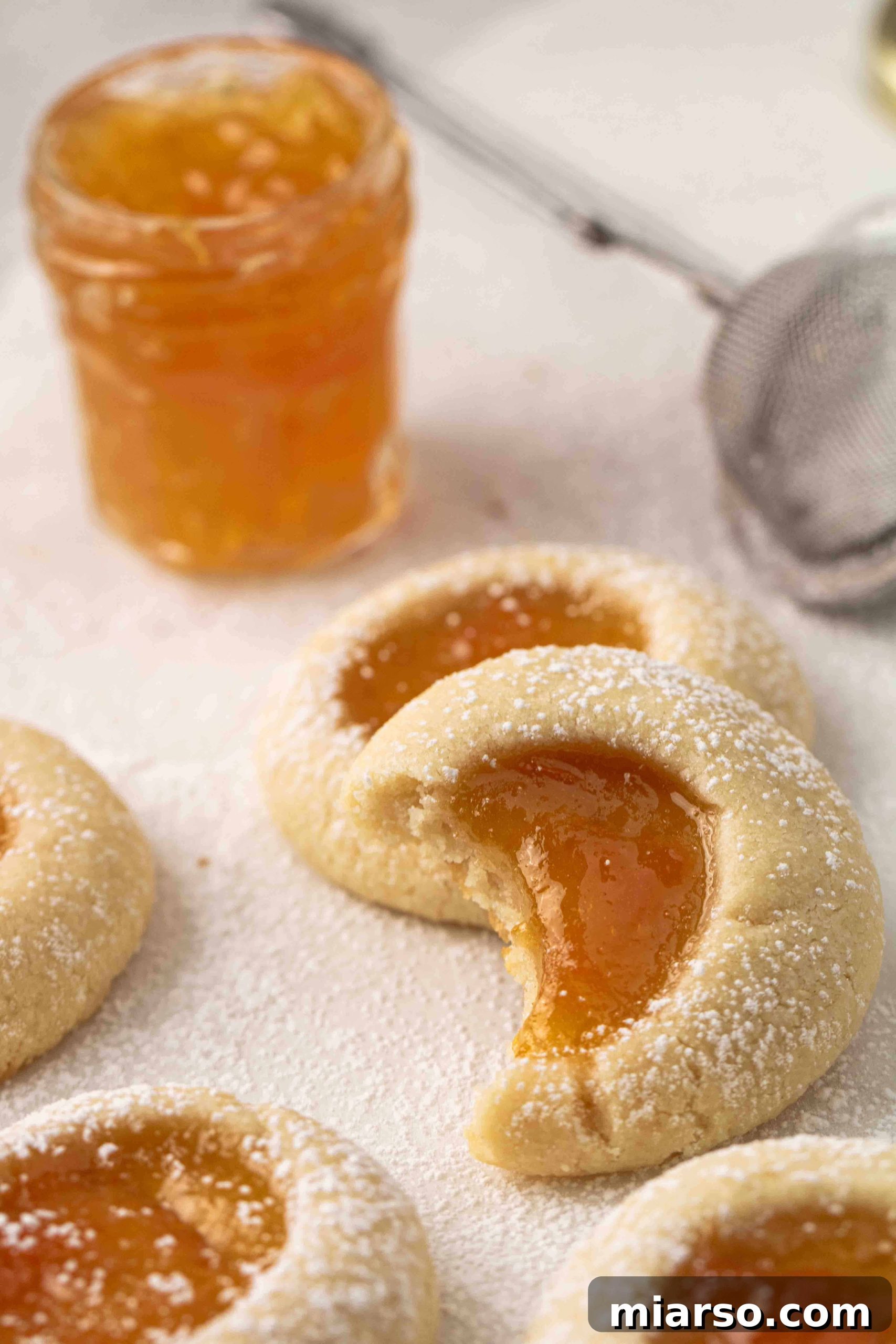 Jam-Kissed Almond Thumbprint Cookies 14 Close-up of perfectly baked apricot jam-filled thumbprint cookies, ready to be enjoyed.