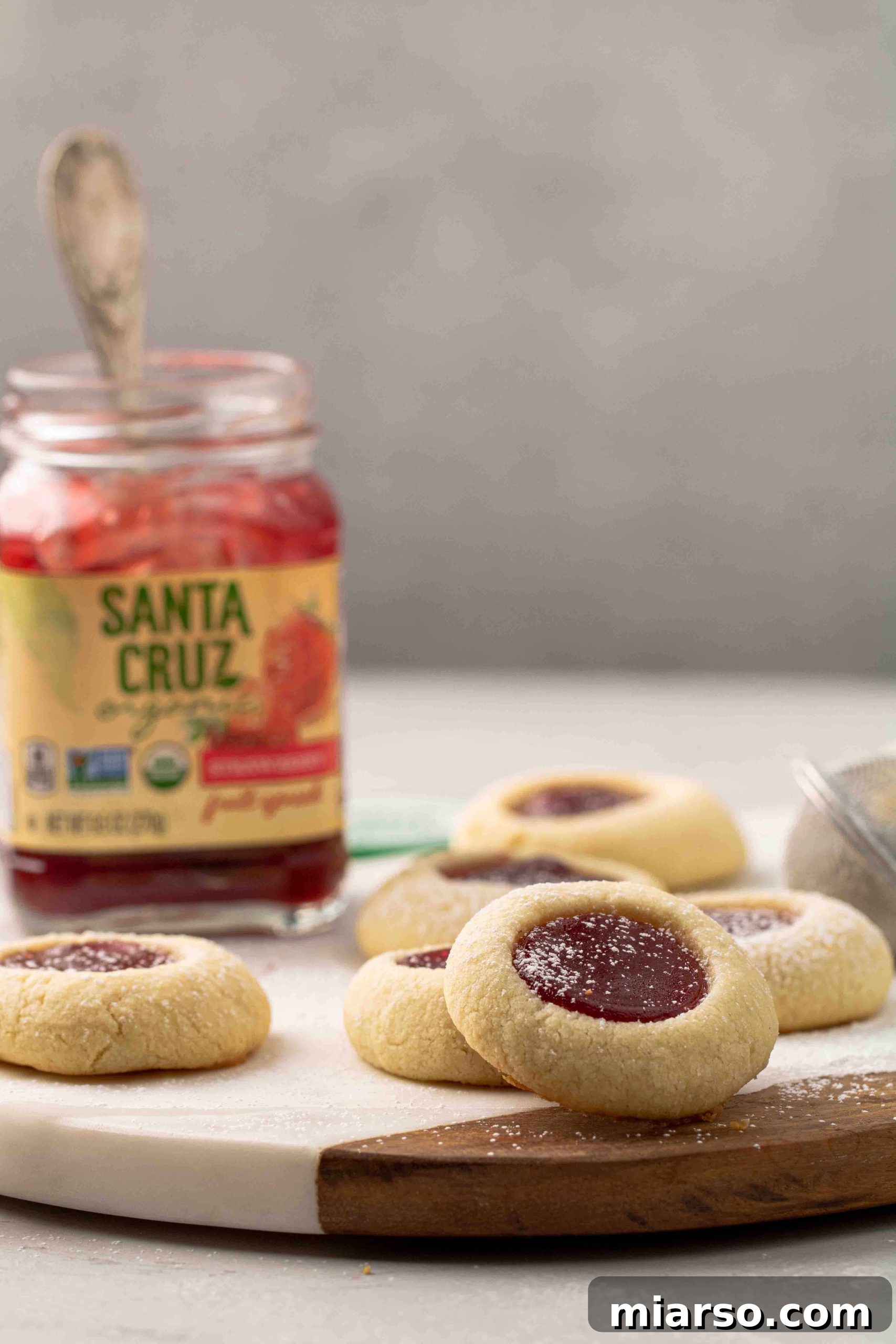 Jam-Kissed Almond Thumbprint Cookies 3 A close-up, straight-on view of freshly baked almond thumbprint cookies, showcasing their perfect shape and golden edges
