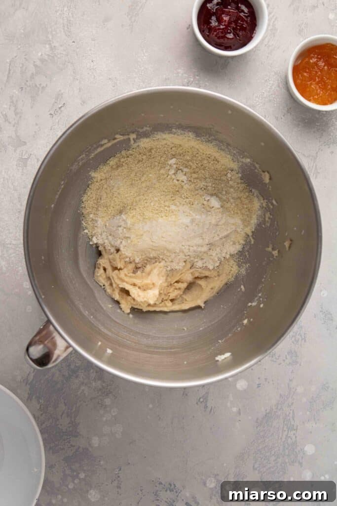Jam-Kissed Almond Thumbprint Cookies 8 Step 2: Adding dry ingredients to the creamed butter mixture.