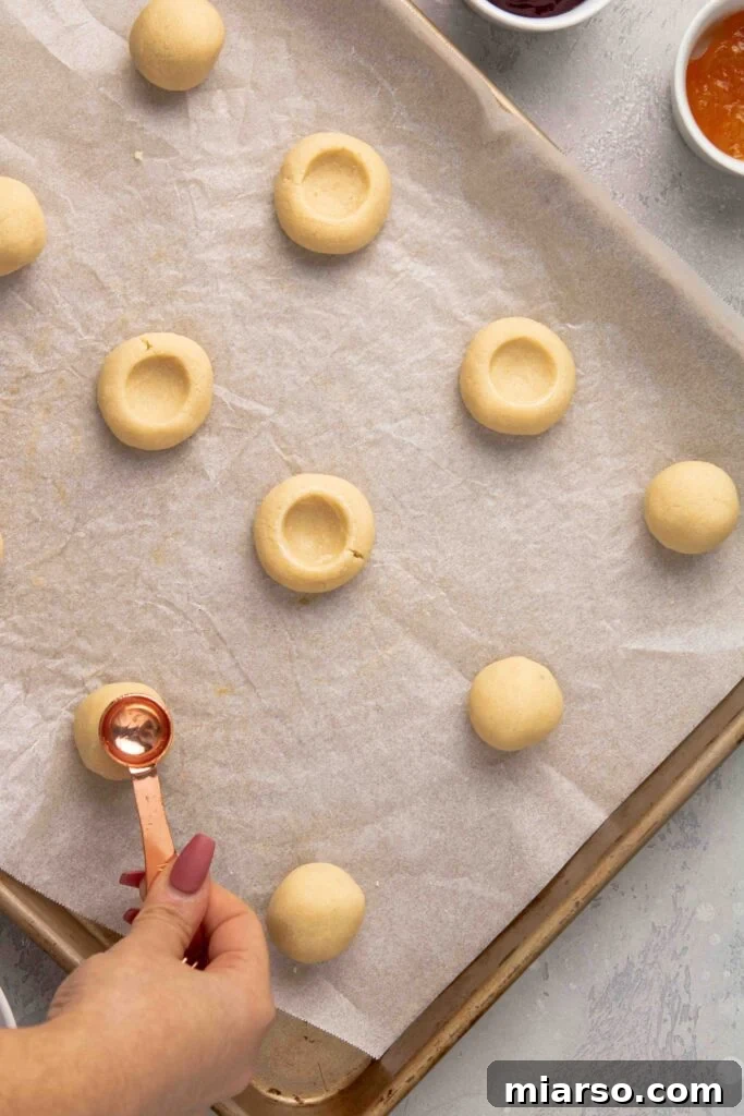Jam-Kissed Almond Thumbprint Cookies 10 Step 4: Creating the thumbprint indentations in the cookie dough balls.