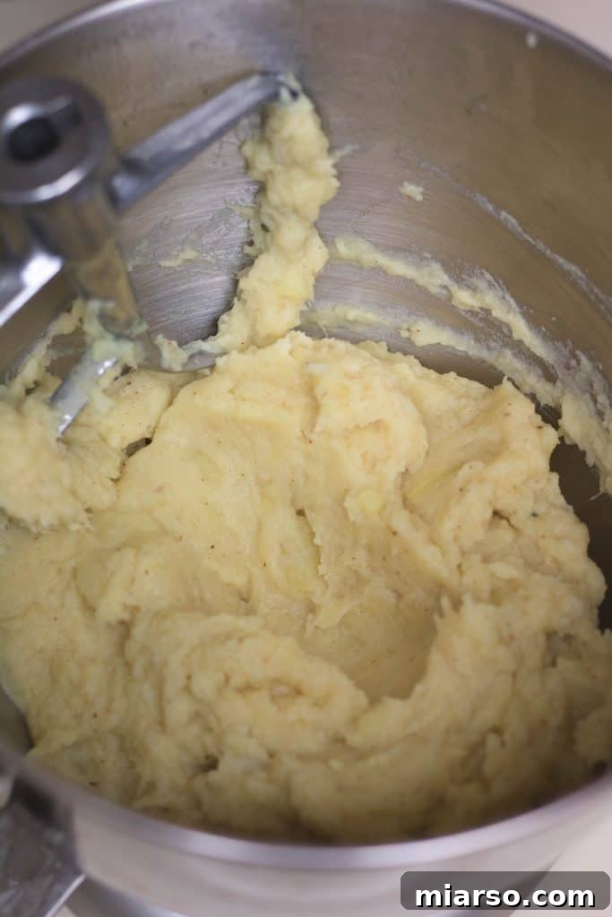 Mixing brown butter and garlic with mashed sweet potatoes.