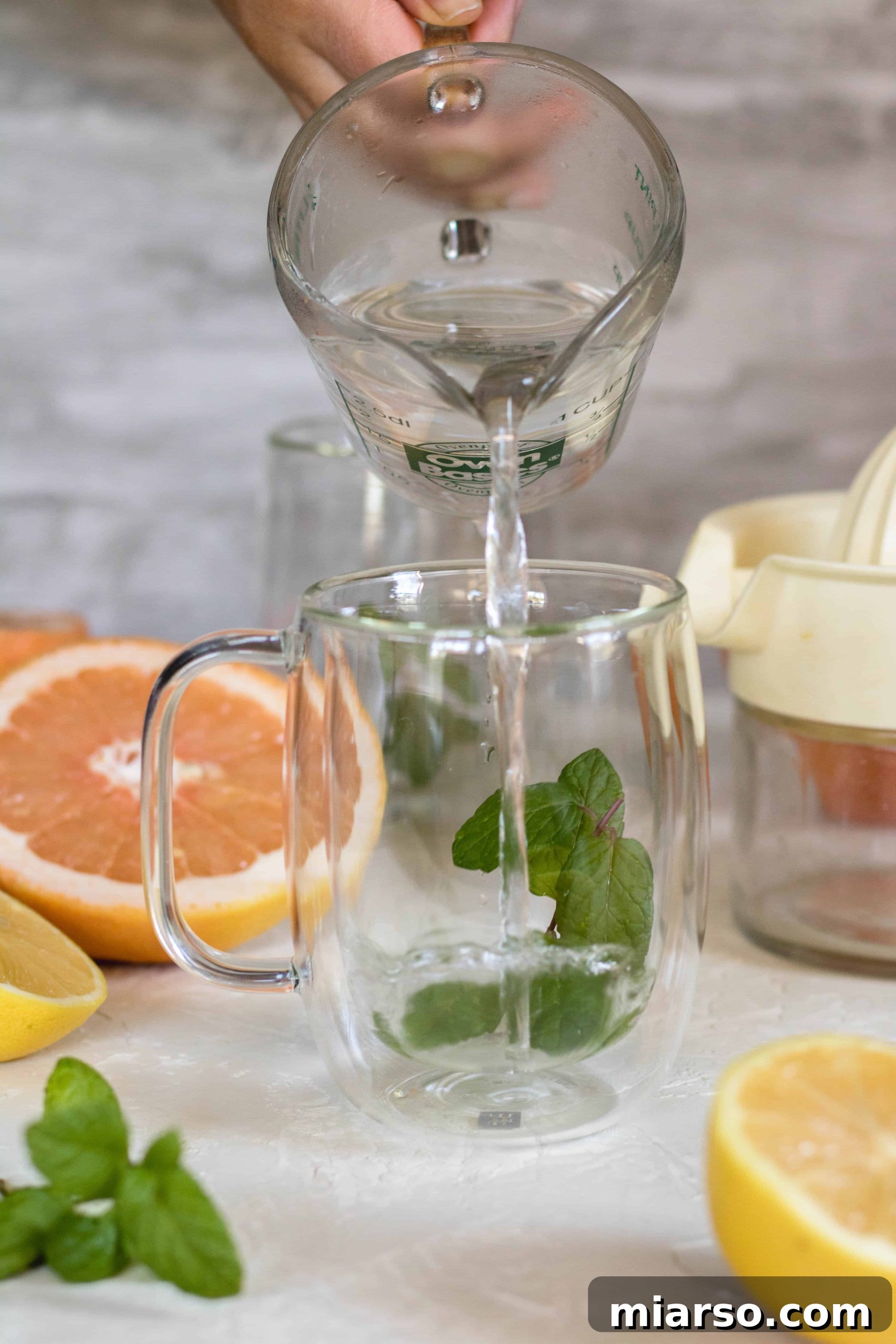 Fresh mint leaves steeping in hot water in a clear mug, preparing the base for detox tea