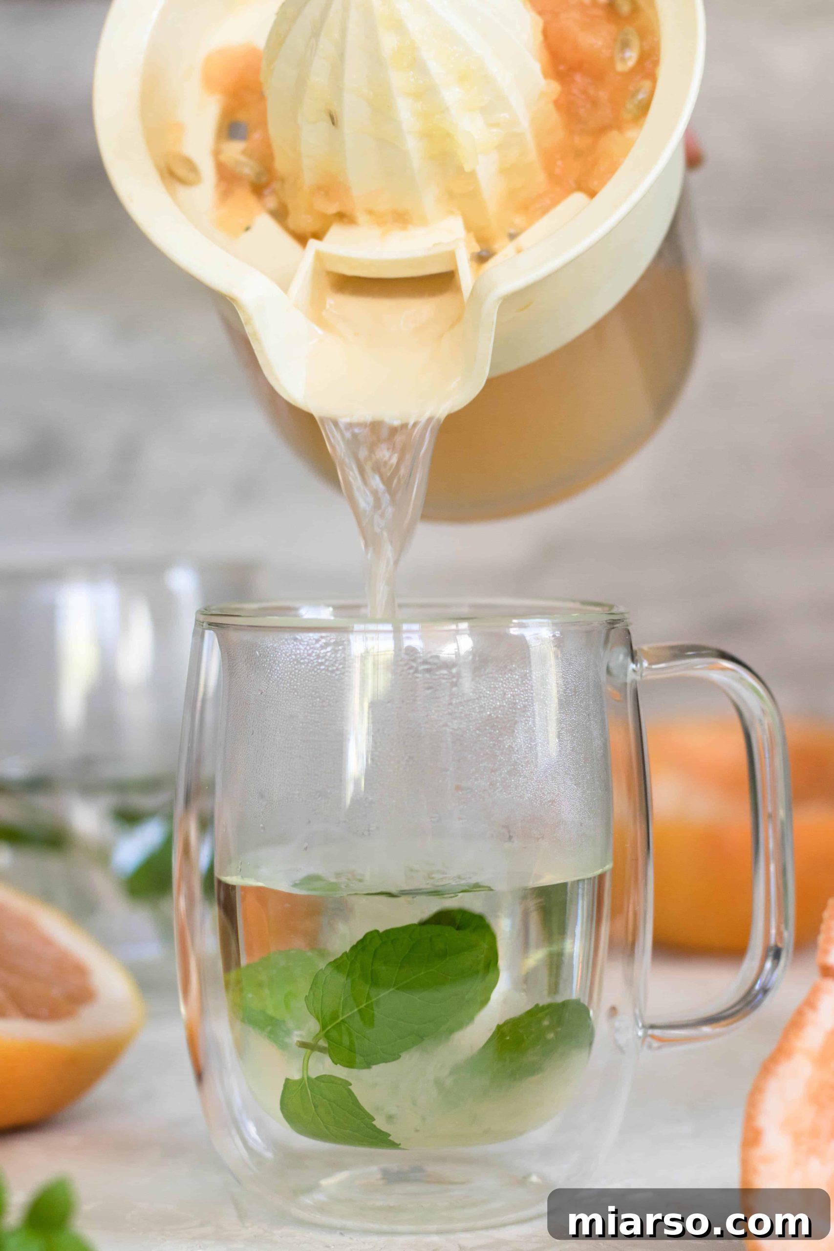 Pouring freshly squeezed citrus juices into a mug of steeped mint tea