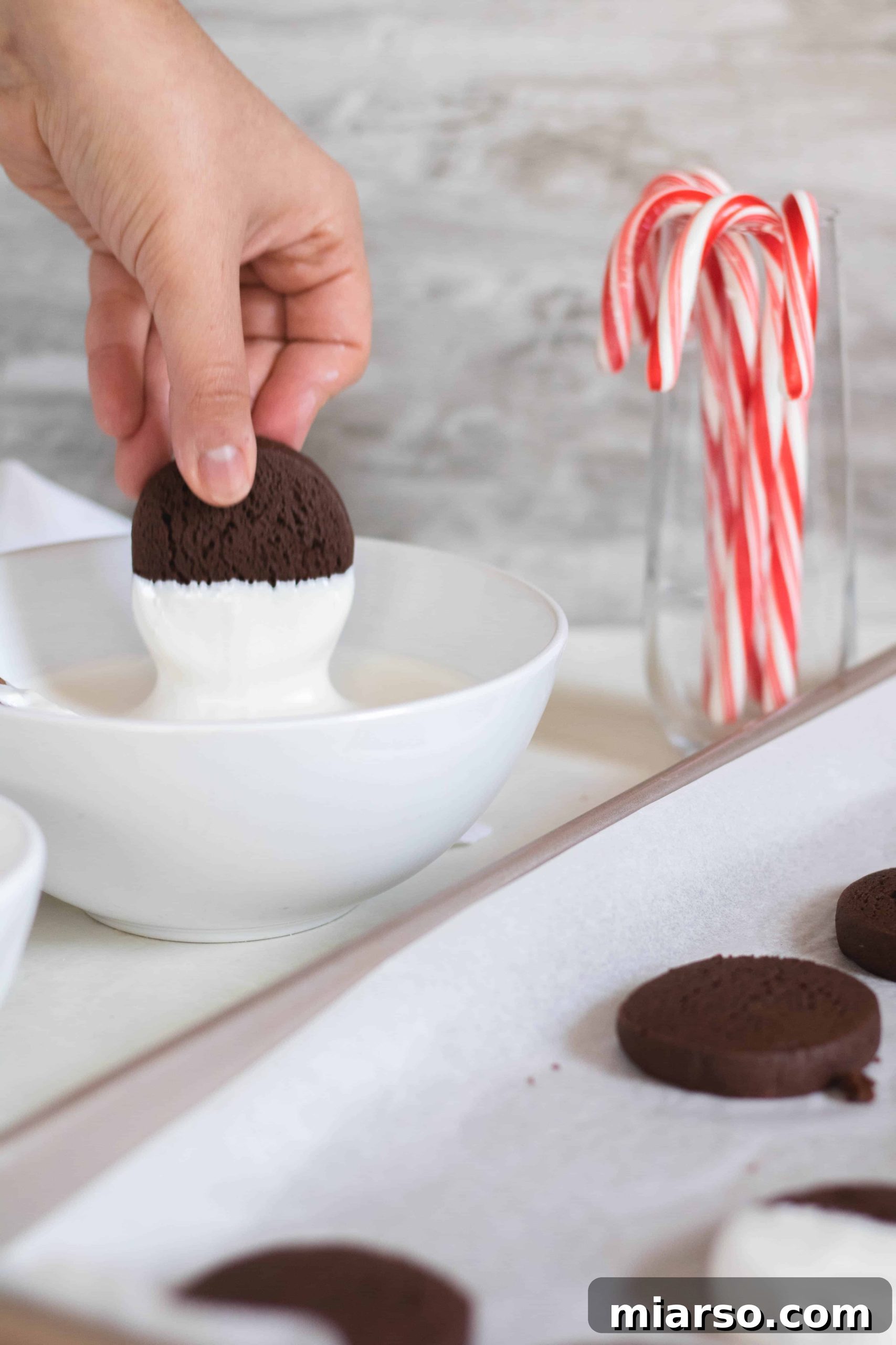 Gourmet Chocolate Peppermint Crunch Logs 10 Step-by-step image of dipping chocolate cookies into white candy melts and sprinkling with crushed candy canes